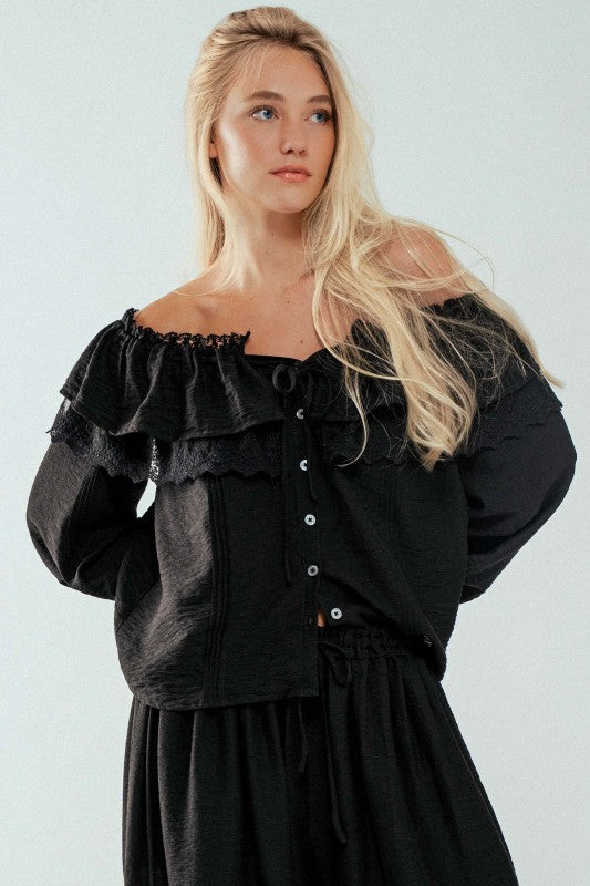 Close-up of romantic lace detailing and layered ruffles on black off-shoulder blouse