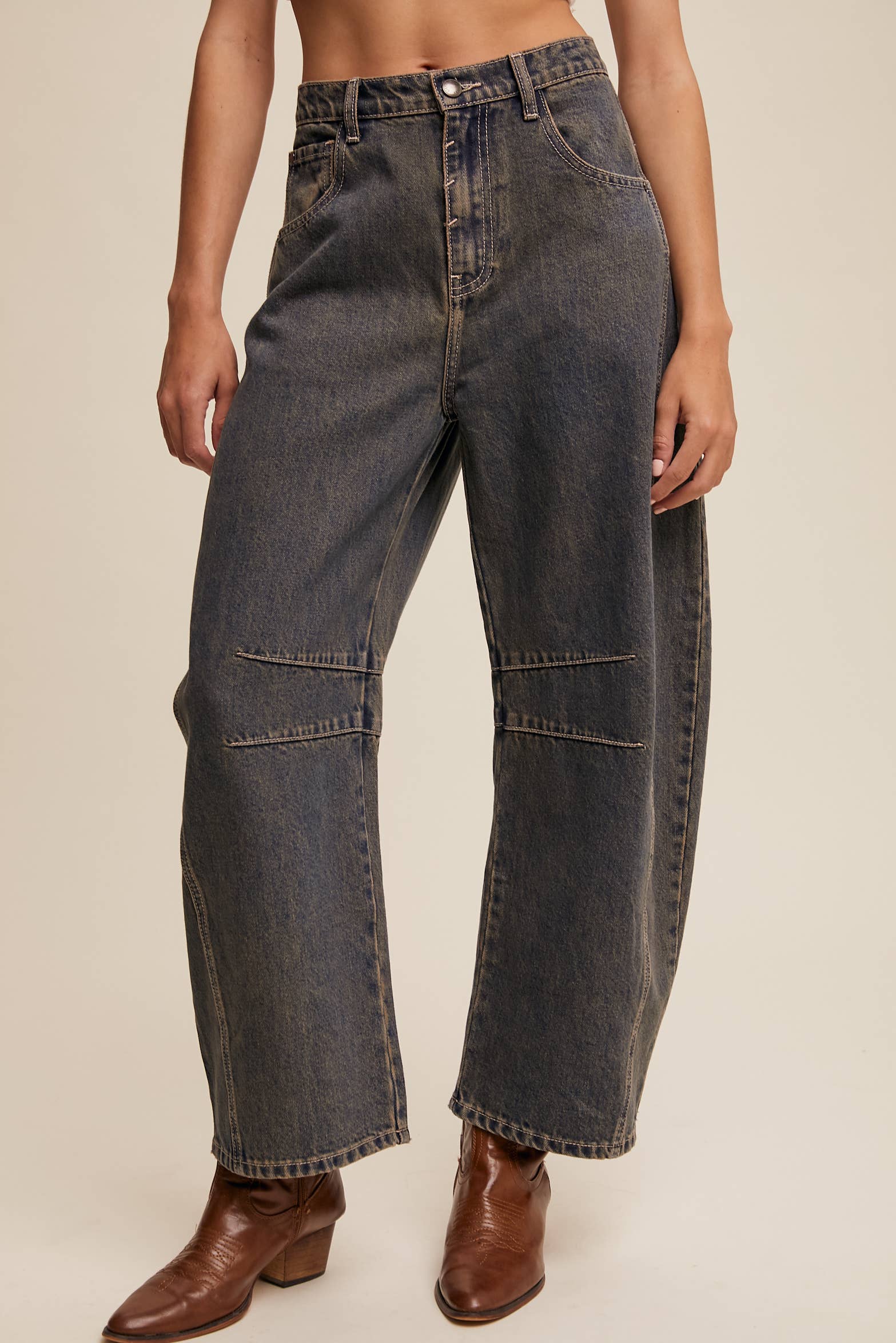 Dark wash wide-leg jeans with relaxed fit, seam detailing across the knees, and a high-rise waist, styled with brown ankle boots.