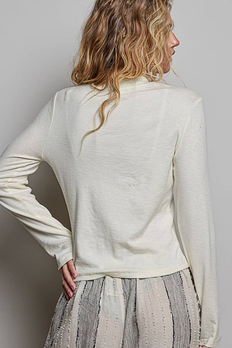 A woman shown from the back wearing a cream-colored long-sleeve knit top and a textured gray skirt against a plain light gray background.