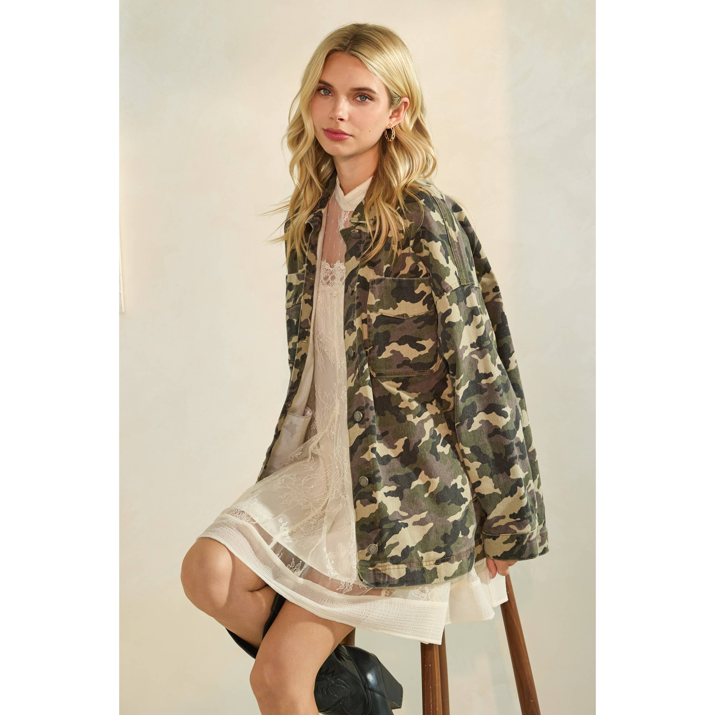 Oversized camouflage print jacket with front pockets and button closure, styled over a white tiered mini dress.