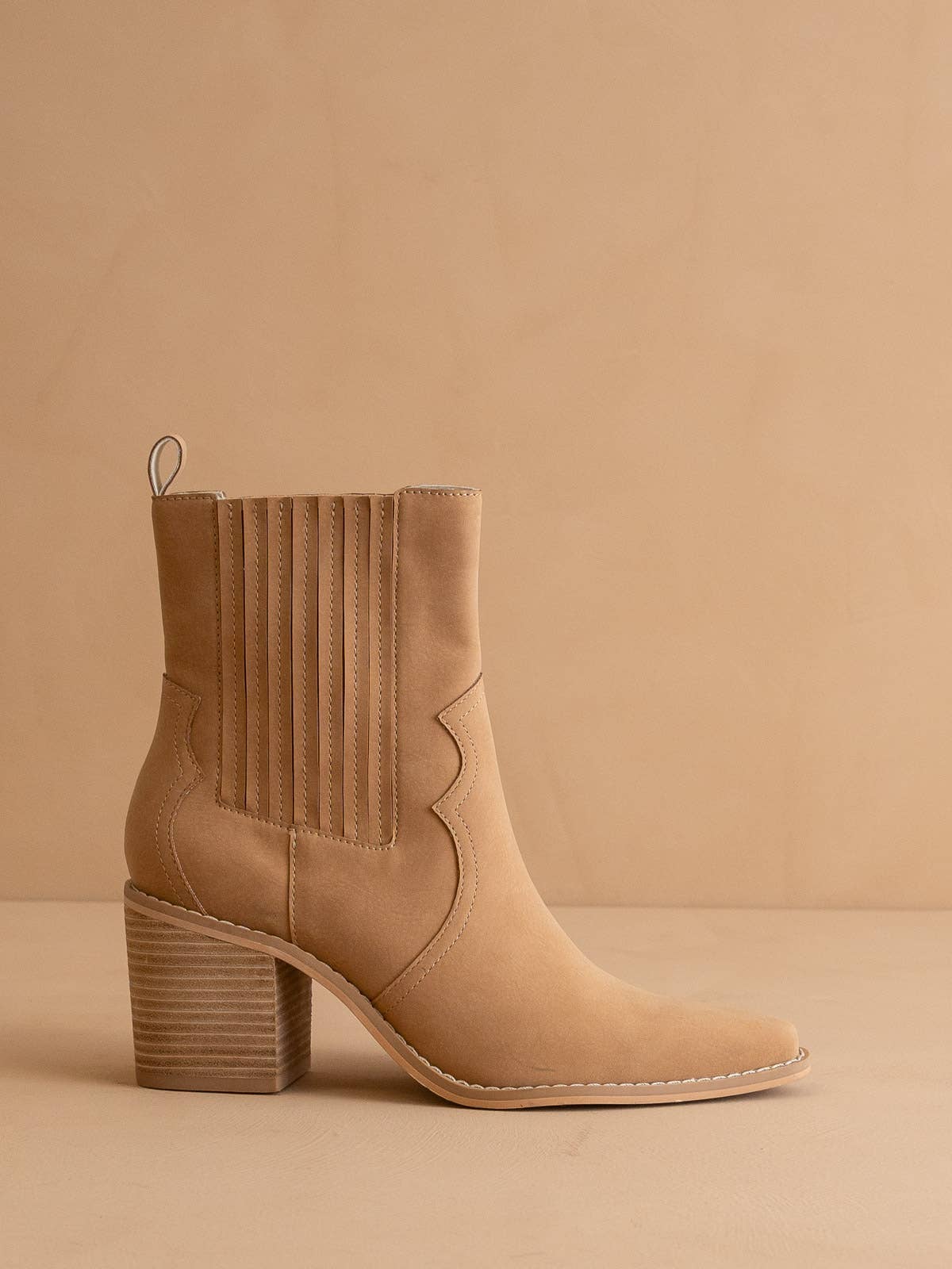 Tan western ankle boot with stacked block heel, pointed toe, ribbed elastic side panel and pull tab, shown on a neutral backdrop.