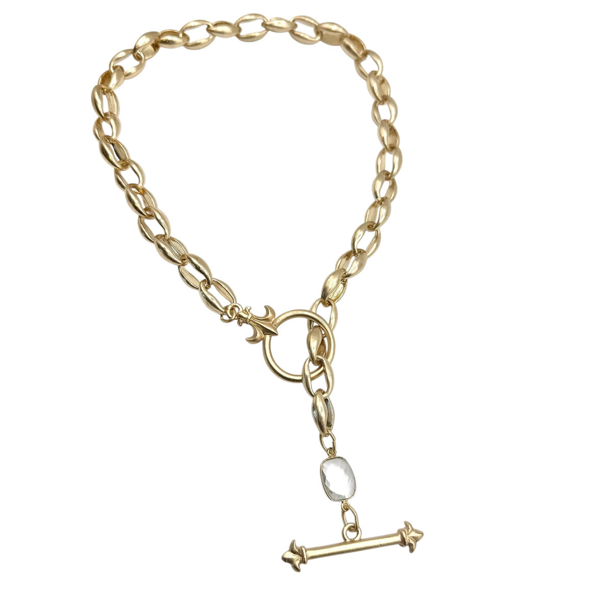 A gold-toned chain bracelet with a toggle clasp, a small clear oval stone, and a dangling T-bar charm, shown on a plain white background.