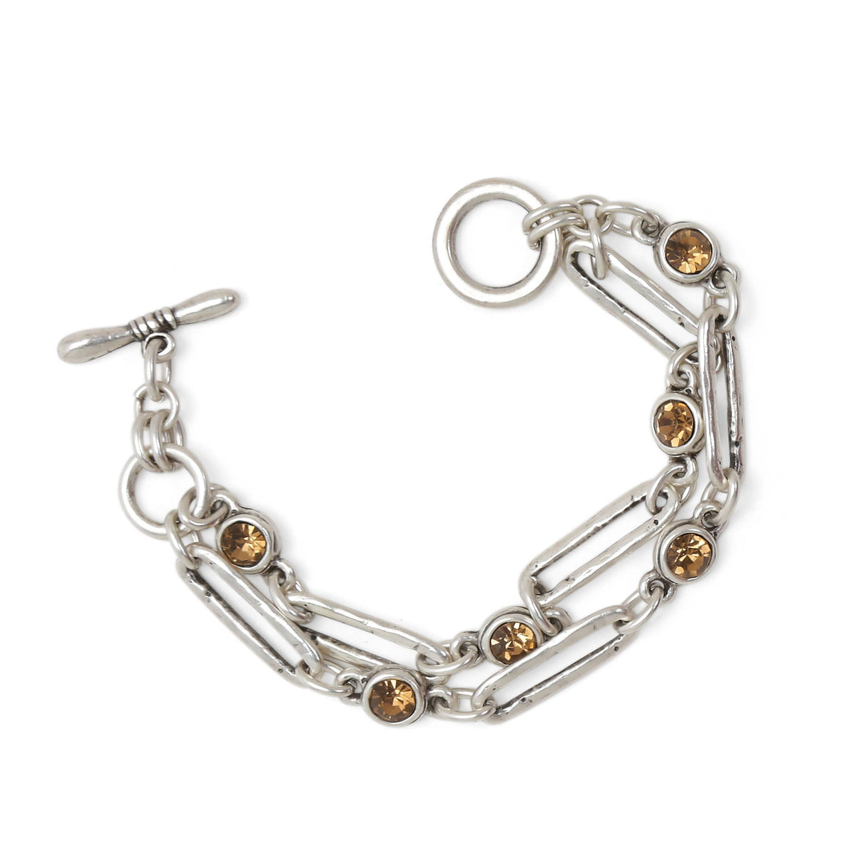 A silver-toned chain bracelet featuring elongated paperclip links, small oval links, and several round amber-brown crystal accents, shown on a plain white background.