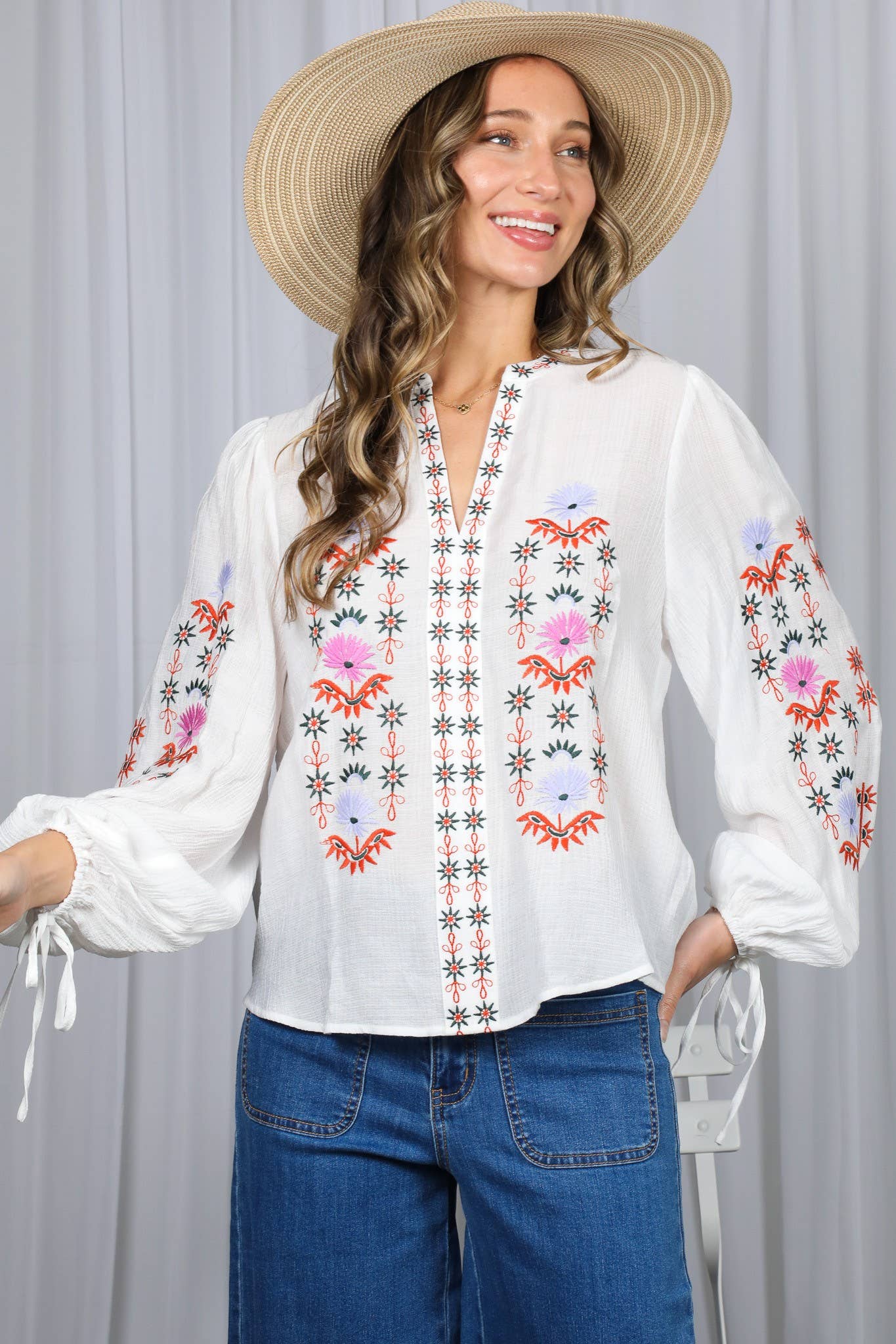 White embroidered peasant blouse with multicolor floral front, split V-neck, and balloon sleeves with ties