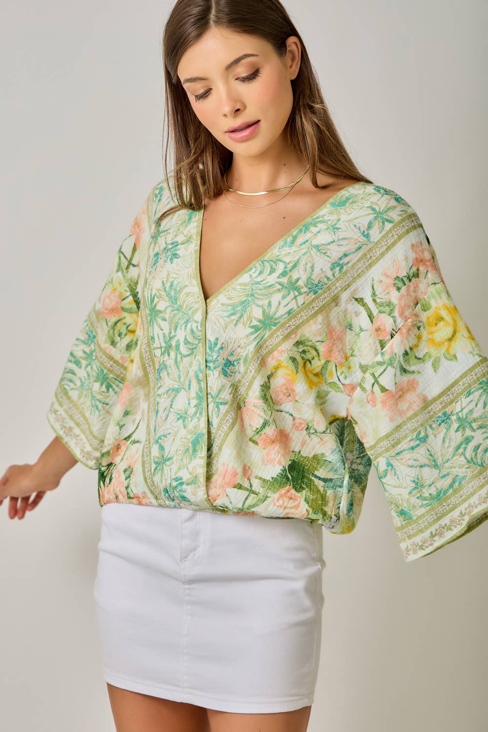 Woman wearing a floral kimono-style top with a plain background