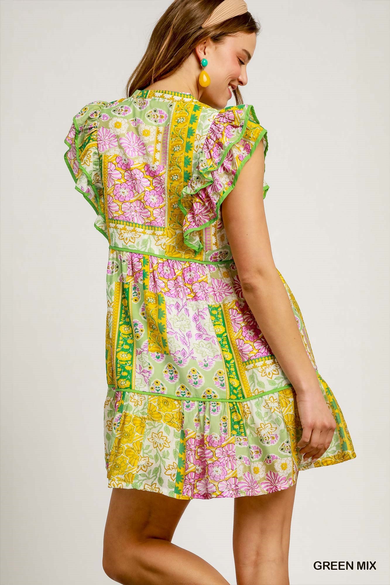 Woman wearing a colorful patchwork dress on a plain background