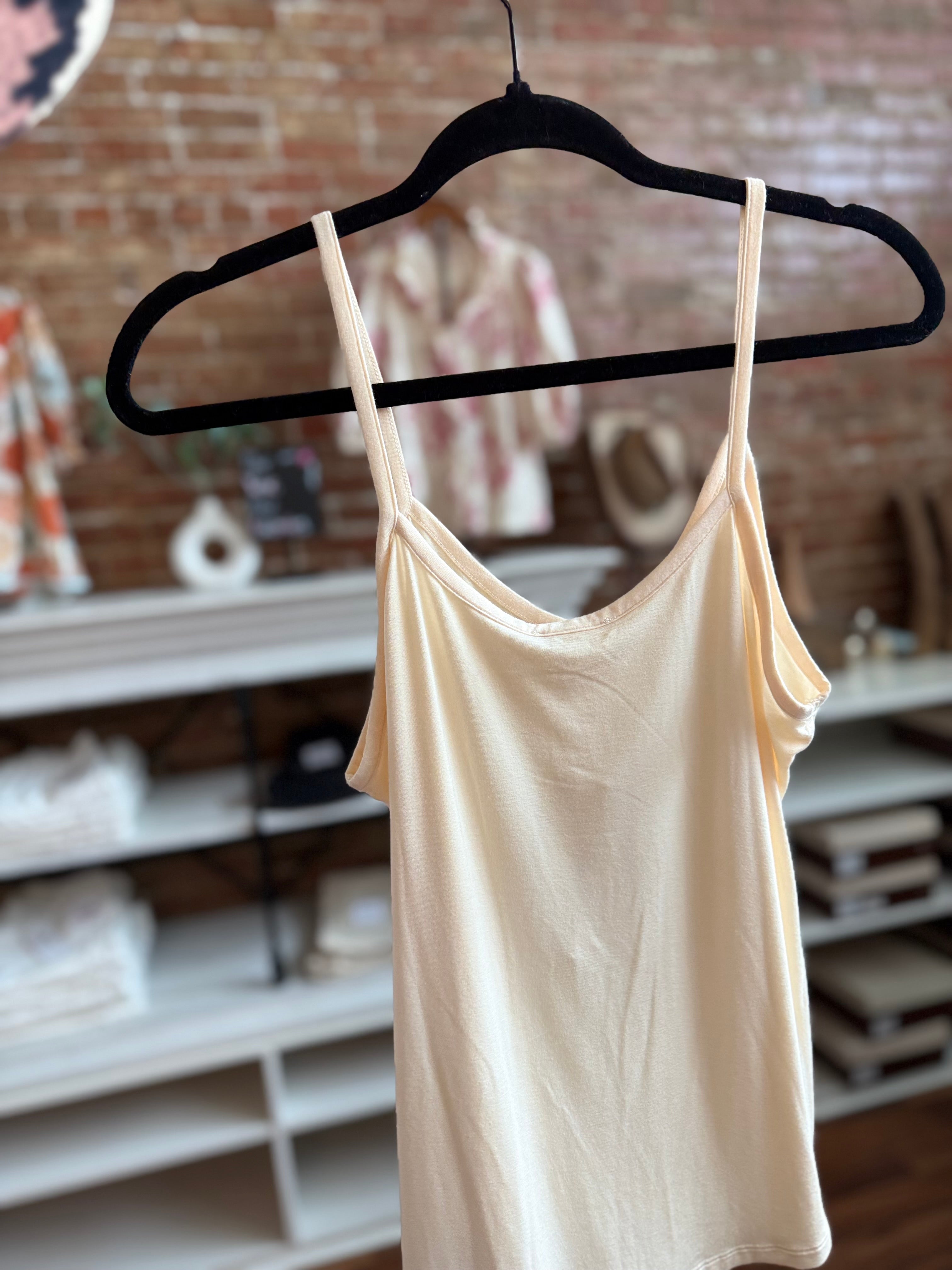 Beige tank top on a hanger against a brick wall background