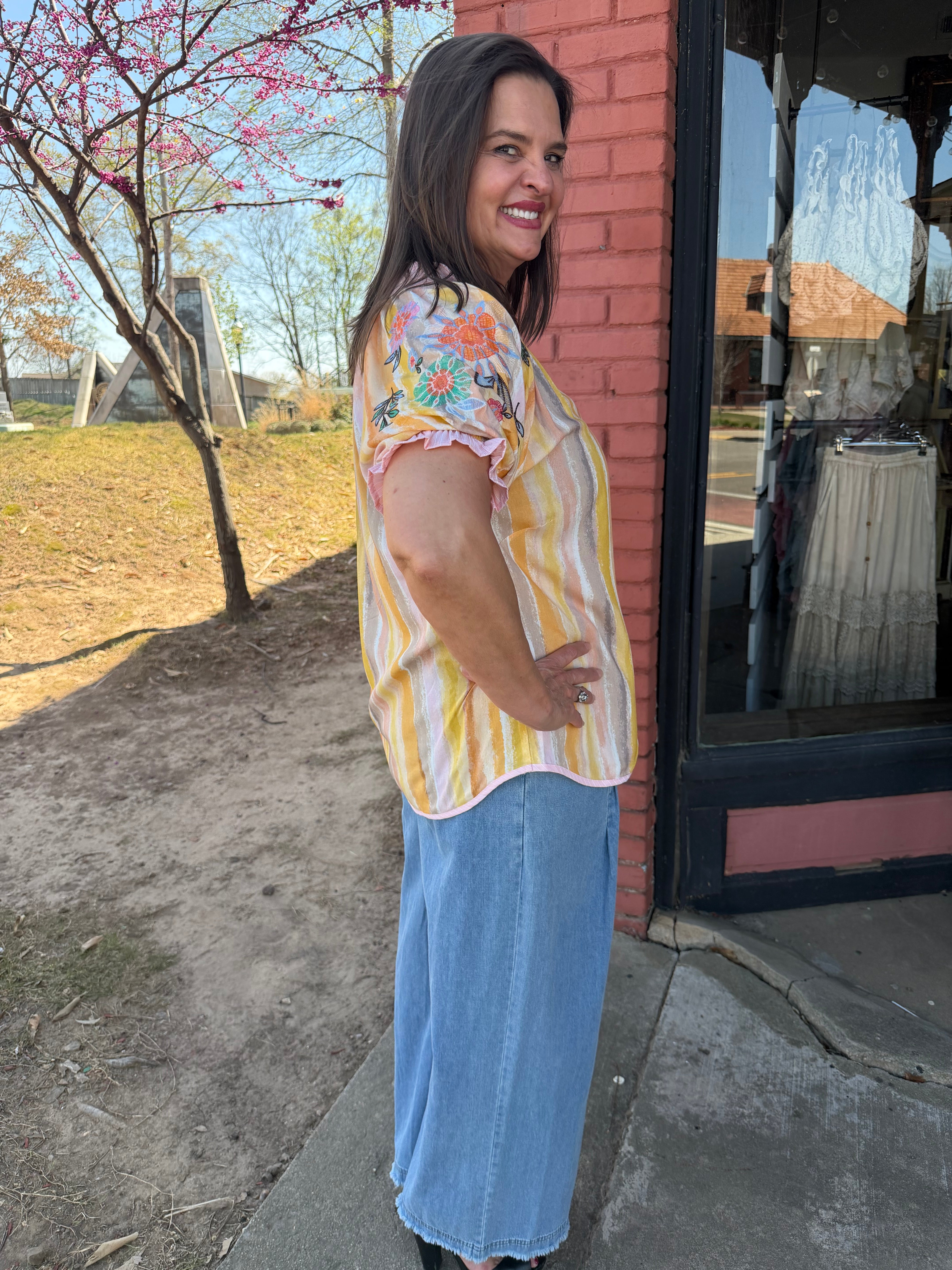 Woman standing outdoors with a tree and building in the background
