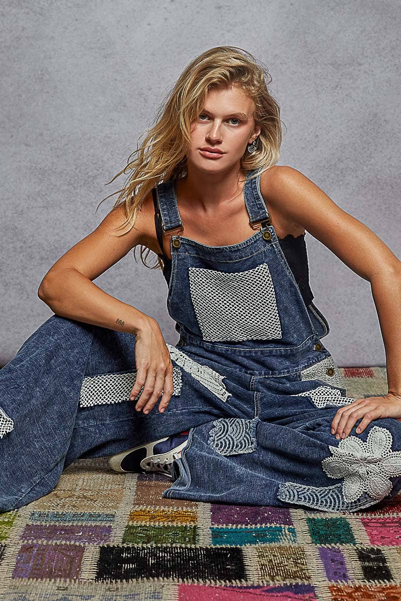 Boho denim patchwork overalls featuring wide legs, crochet lace appliqué patches, and vintage-inspired distressed detailing. Styled with a black crop top and sneakers for a relaxed, eclectic look.”

