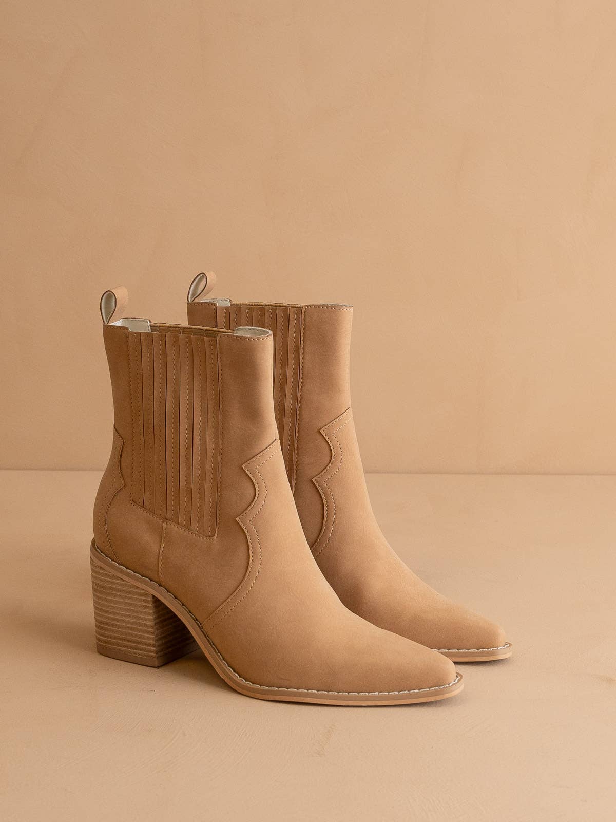 Tan western ankle boot with stacked block heel, pointed toe, ribbed elastic side panel and pull tab, shown on a neutral backdrop.