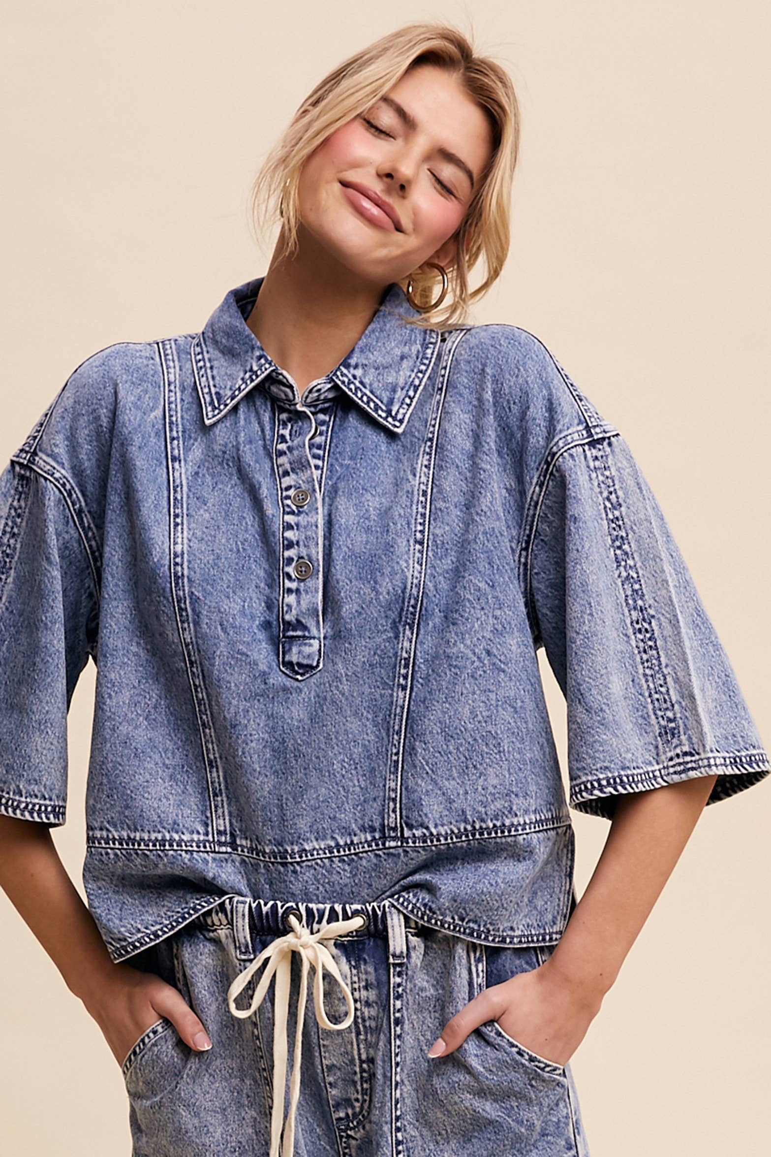 Light-wash denim pullover top with a half-button placket, exposed seam panels, and wide elbow-length sleeves in a relaxed, boxy fit.