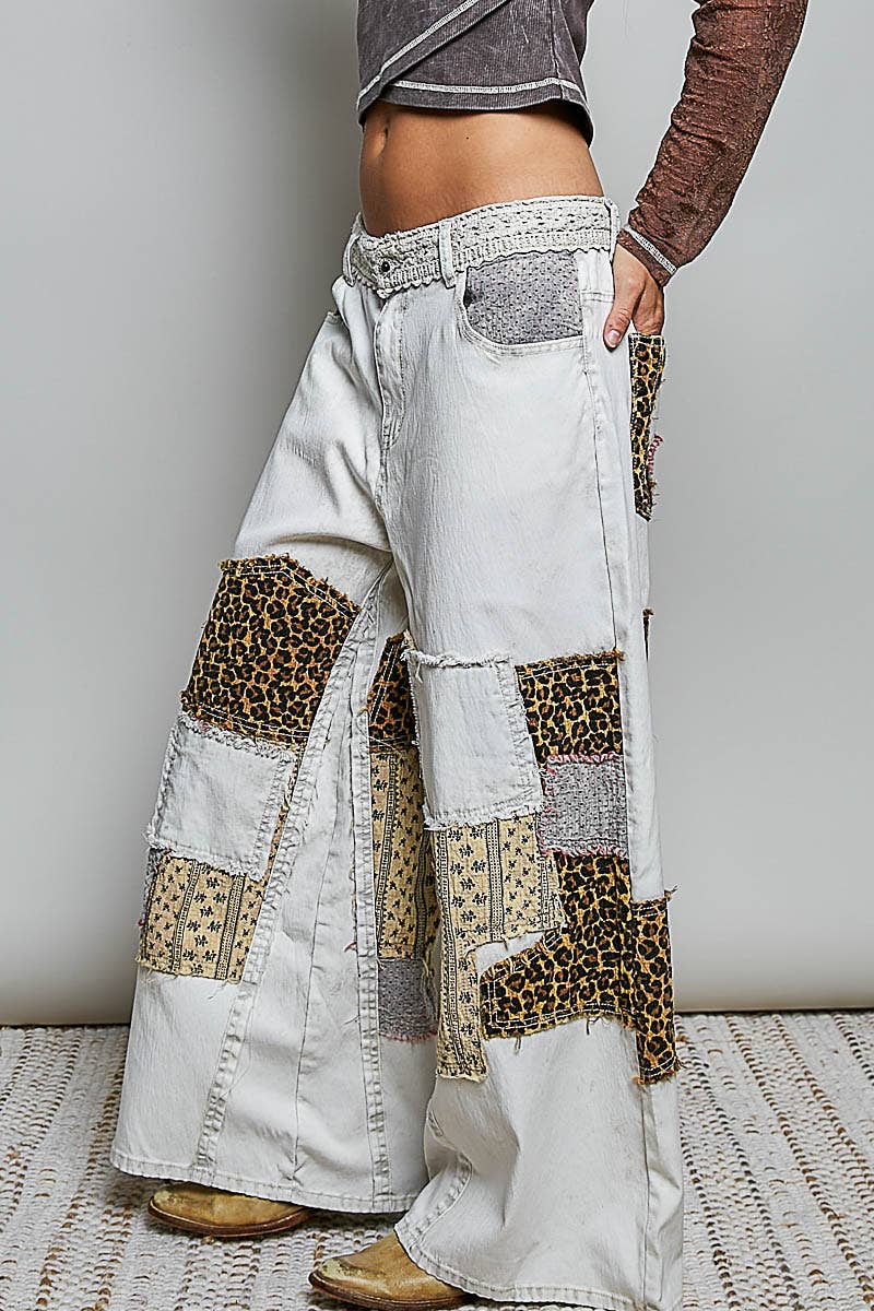 White patchwork pants with leopard print details worn by a person on a neutral background