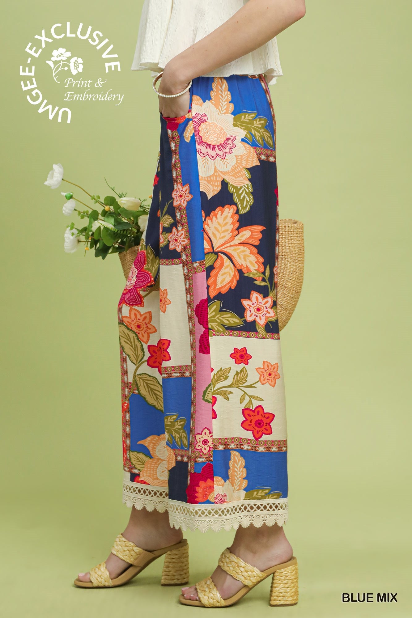 Woman wearing a colorful floral and patchwork skirt with a green background