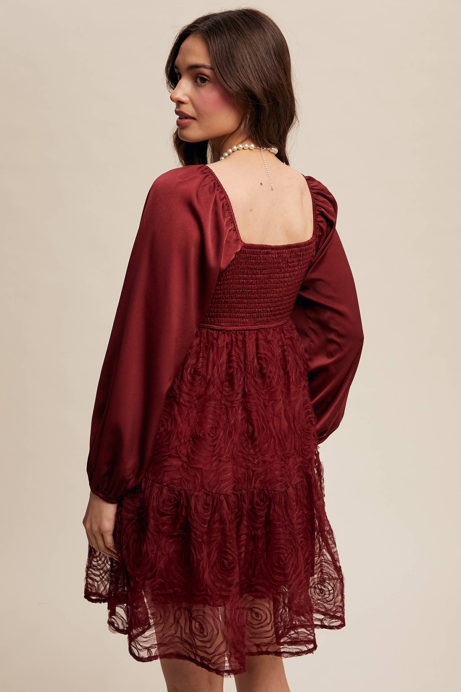 Back view of Model wearing oxblood red rosette mini dress with ruched sweetheart neckline, puff long sleeves, and tiered lace skirt — elegant and romantic look.