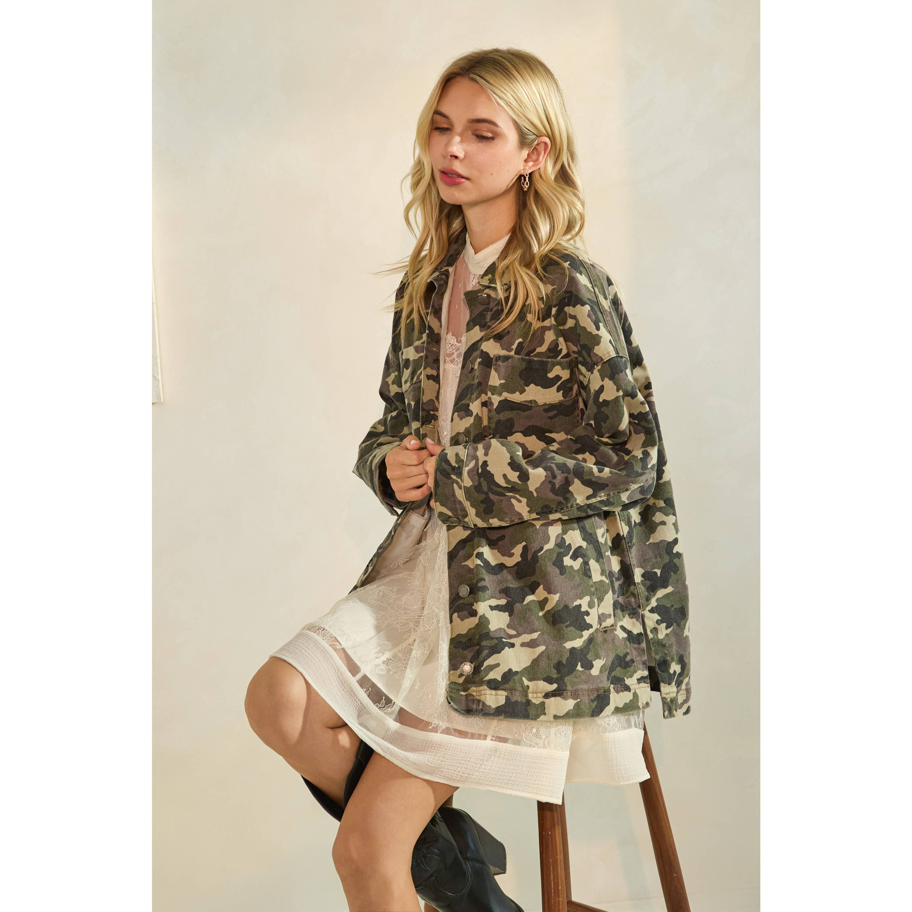 Oversized camouflage print jacket with front pockets and button closure, styled over a white tiered mini dress.