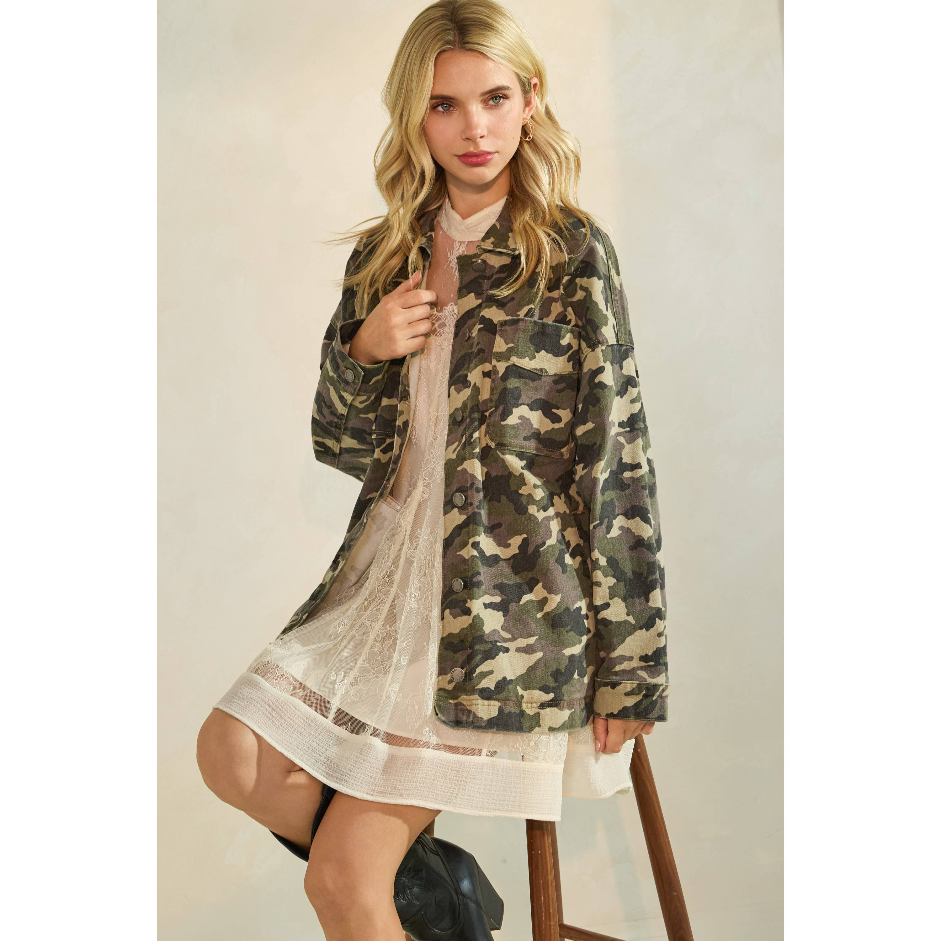 Oversized camouflage print jacket with front pockets and button closure, styled over a white tiered mini dress.