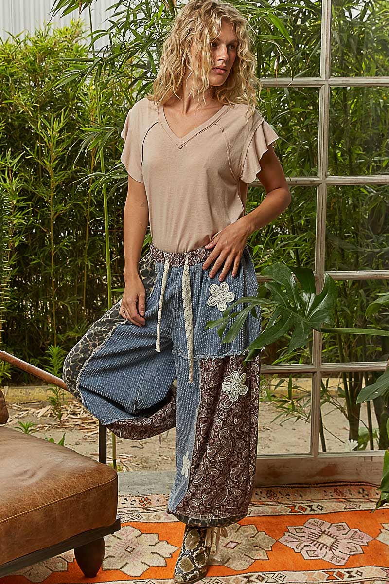 Woman in a casual outfit standing in a garden with plants and a window in the background