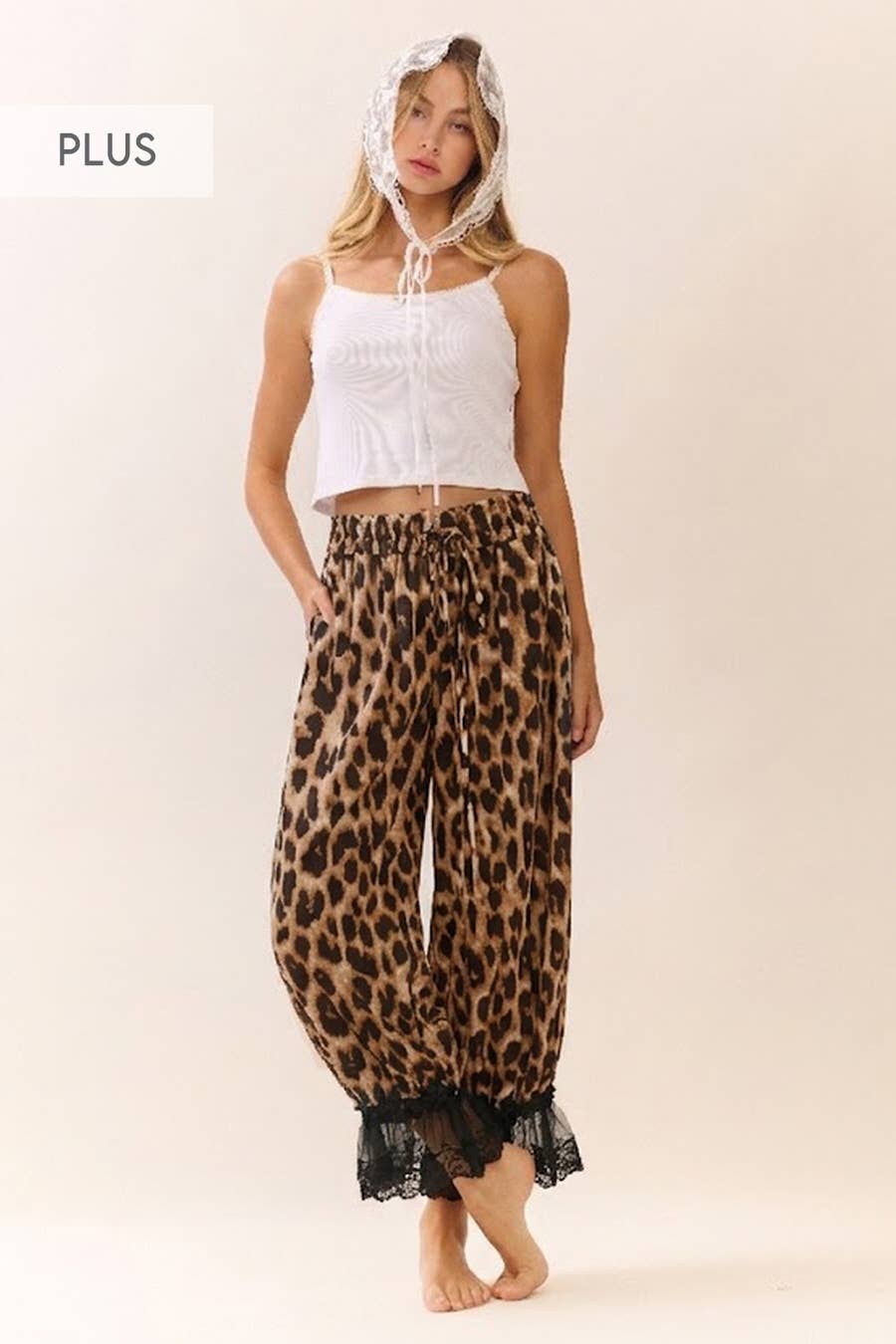 Woman wearing leopard print pants with a white top on a beige background
