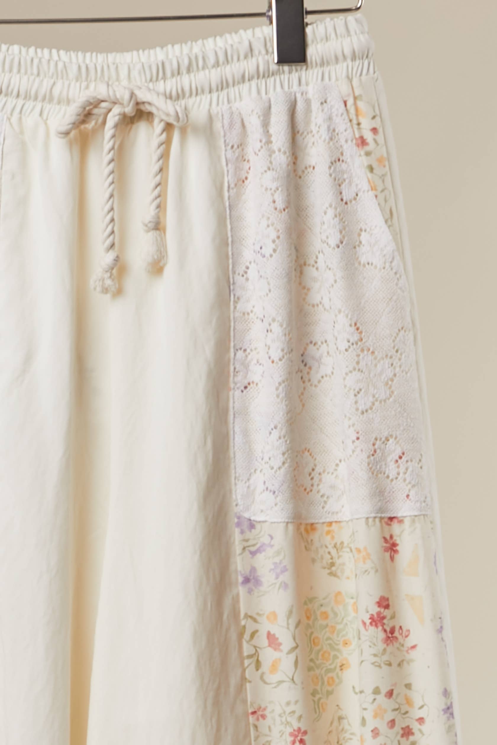 Floral ruffle pants detail shot - artisan patchwork construction with whimsical romantic accents