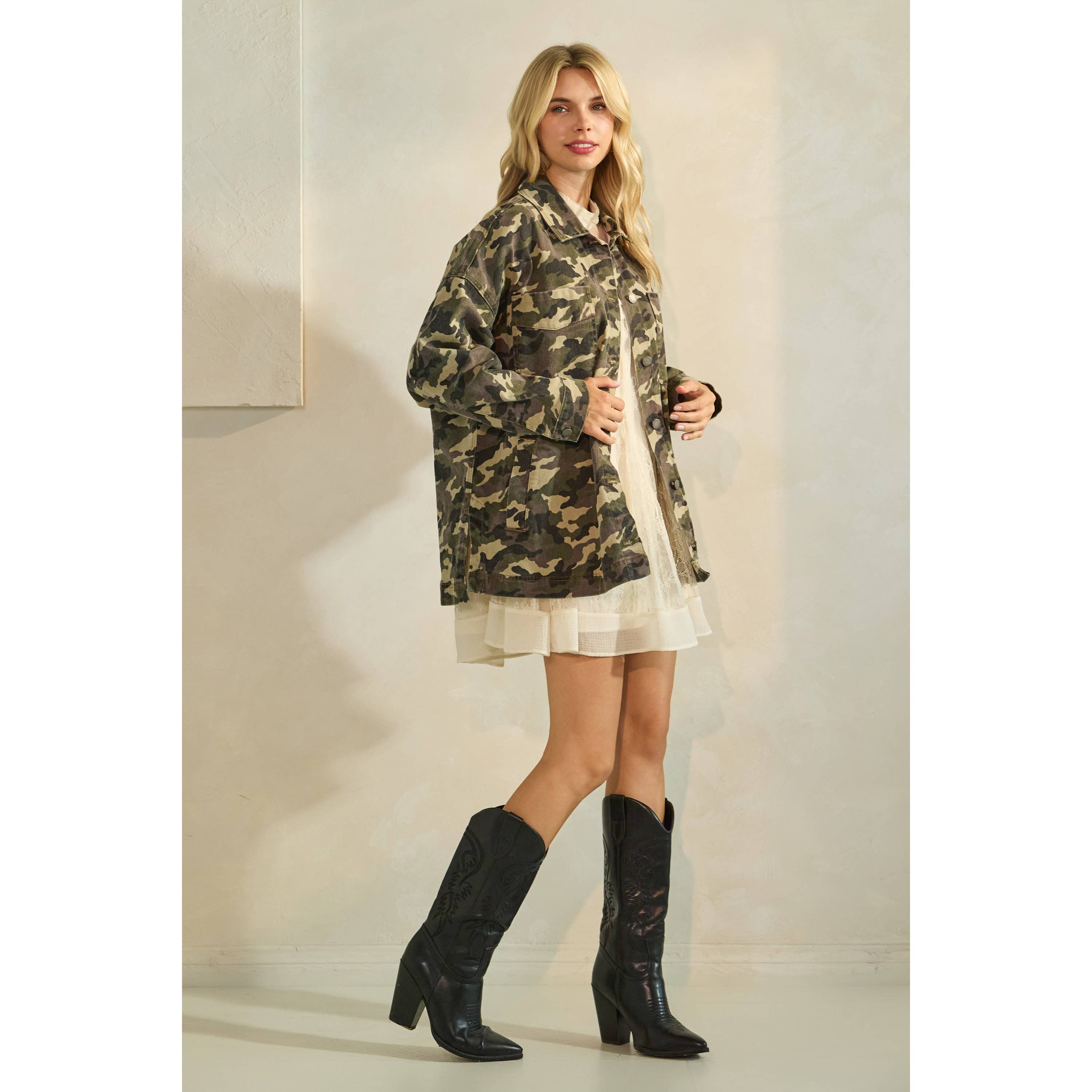 Oversized camouflage print jacket with front pockets and button closure, styled over a white tiered mini dress.