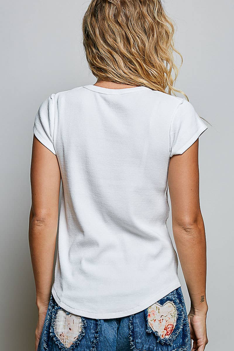 Back view of white artisan stitch curved hem knit top showing curved hem and rib knit texture, styled with heart appliqué patchwork wide-leg jeans 