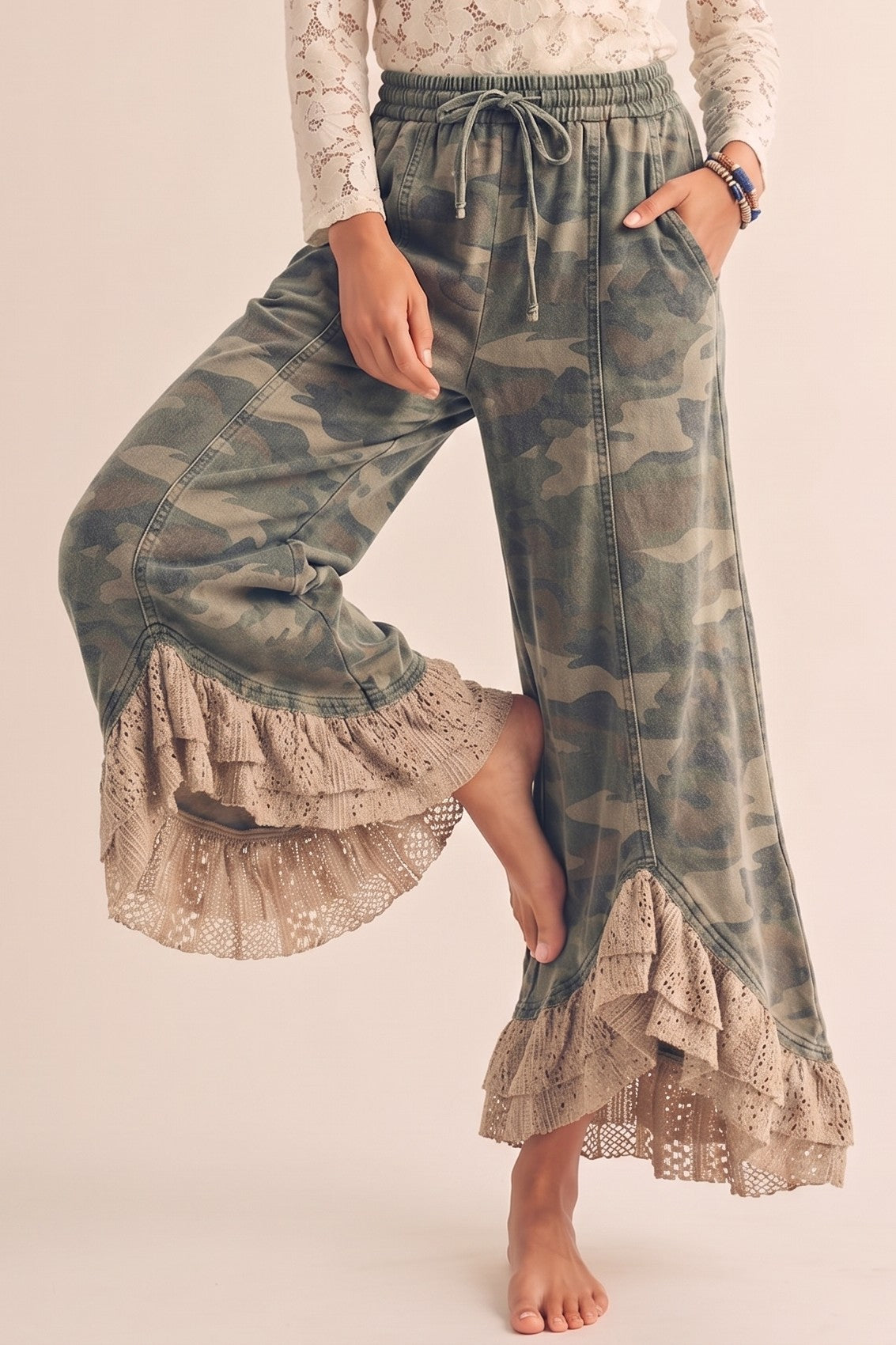 Camouflage pants with lace ruffles worn by a person on a plain background