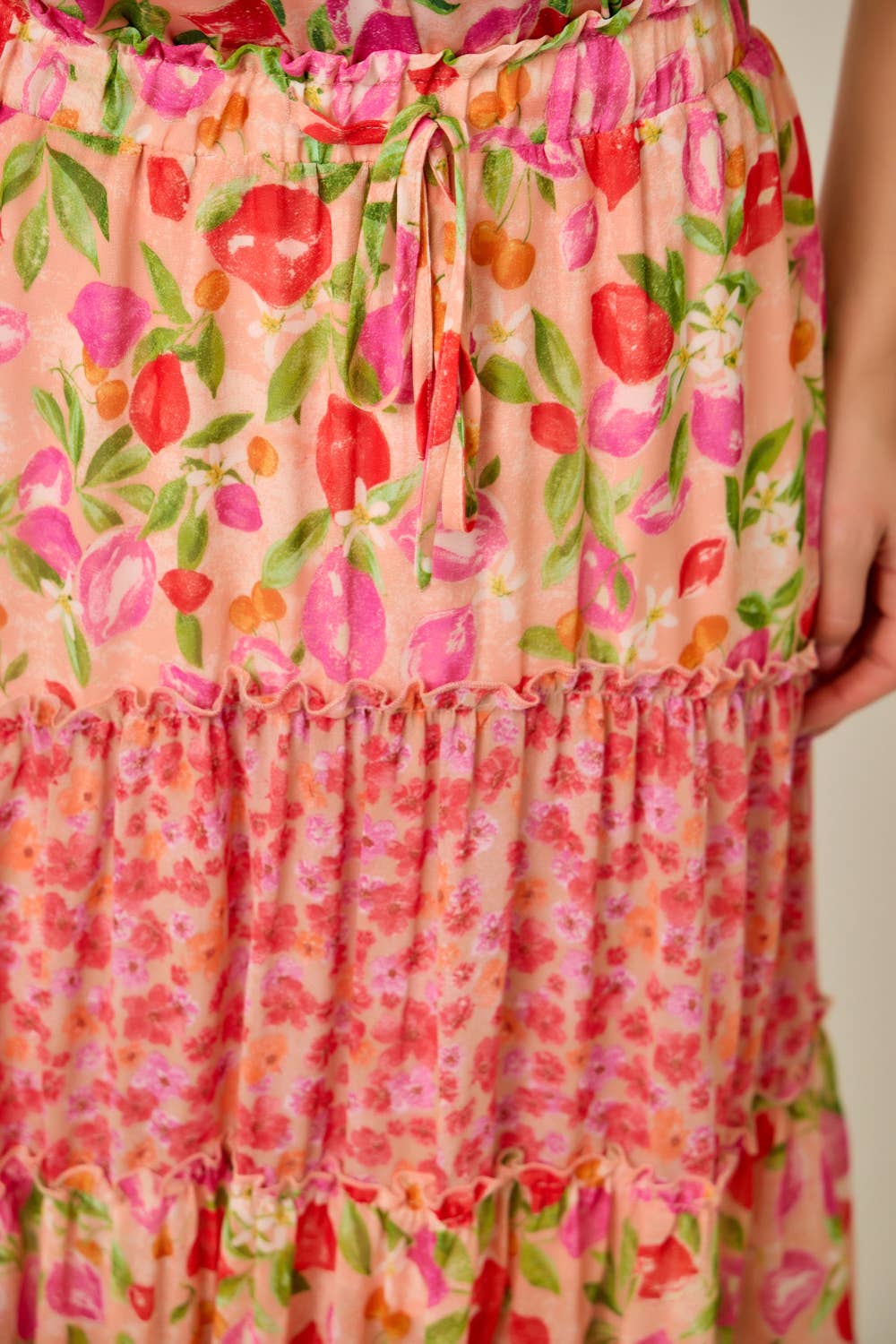 Close-up of a floral dress with pink, red, and green colors on a plain background