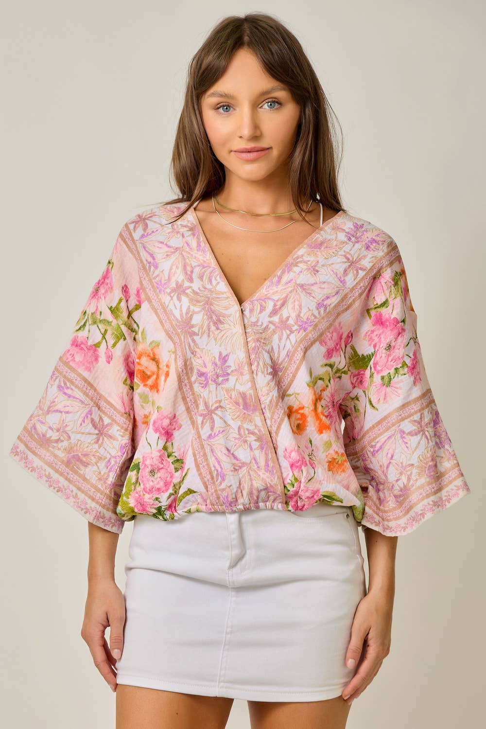 Woman wearing a floral kimono-style top with a plain background