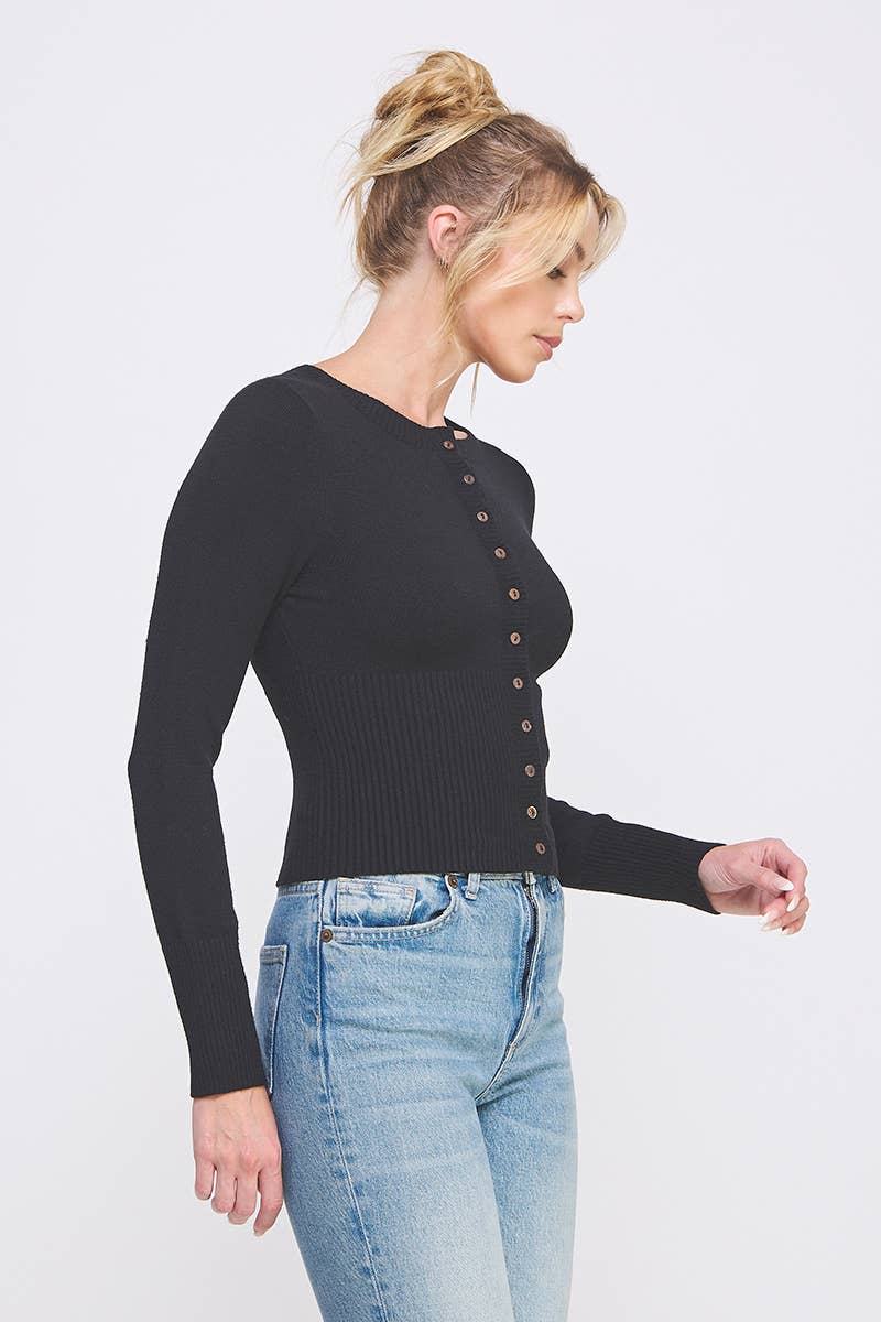 Side view of woman wearing a black ribbed sweater with button details 