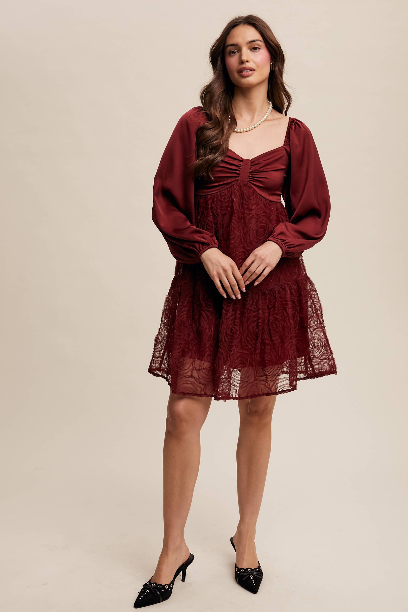 Model wearing oxblood red rosette mini dress with ruched sweetheart neckline, puff long sleeves, and tiered lace skirt — elegant and romantic look.