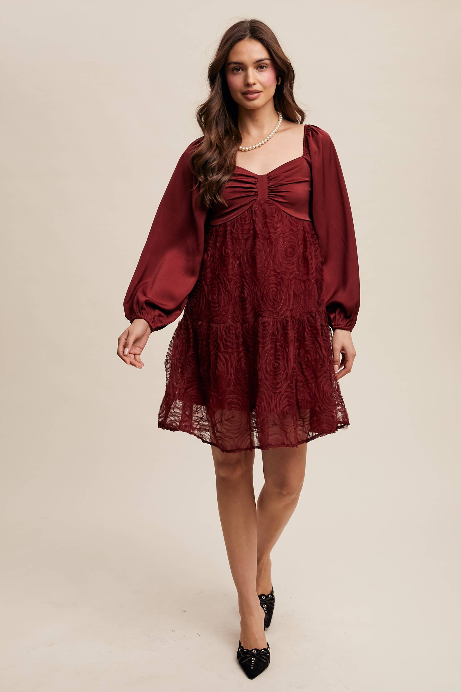 Model wearing oxblood red rosette mini dress with ruched sweetheart neckline, puff long sleeves, and tiered lace skirt — elegant and romantic look.