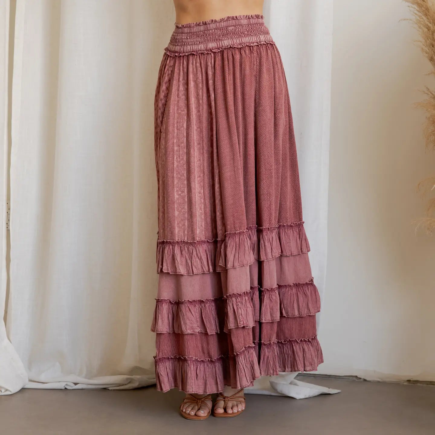 Garnet Artisan Panel Maxi Skirt - front view showing smocked waist, mixed texture panels, and layered ruffle hem styled with strappy sandals