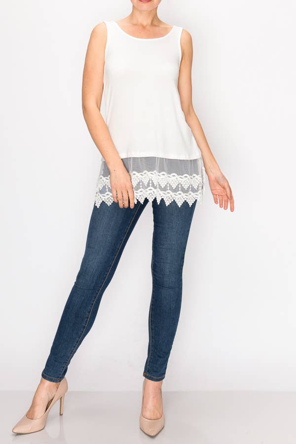 Woman wearing a white sleeveless top with lace trim and blue jeans on a white background