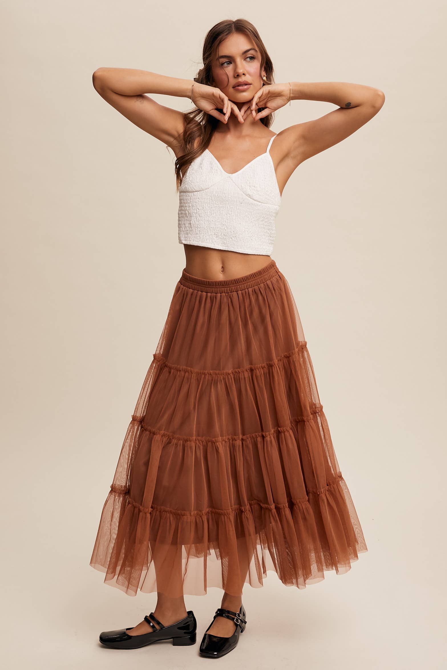 Front view — rust tulle tiered midi skirt with elastic waist and ruffle tiers, sheer overlay; model in black Mary Jane flats.
