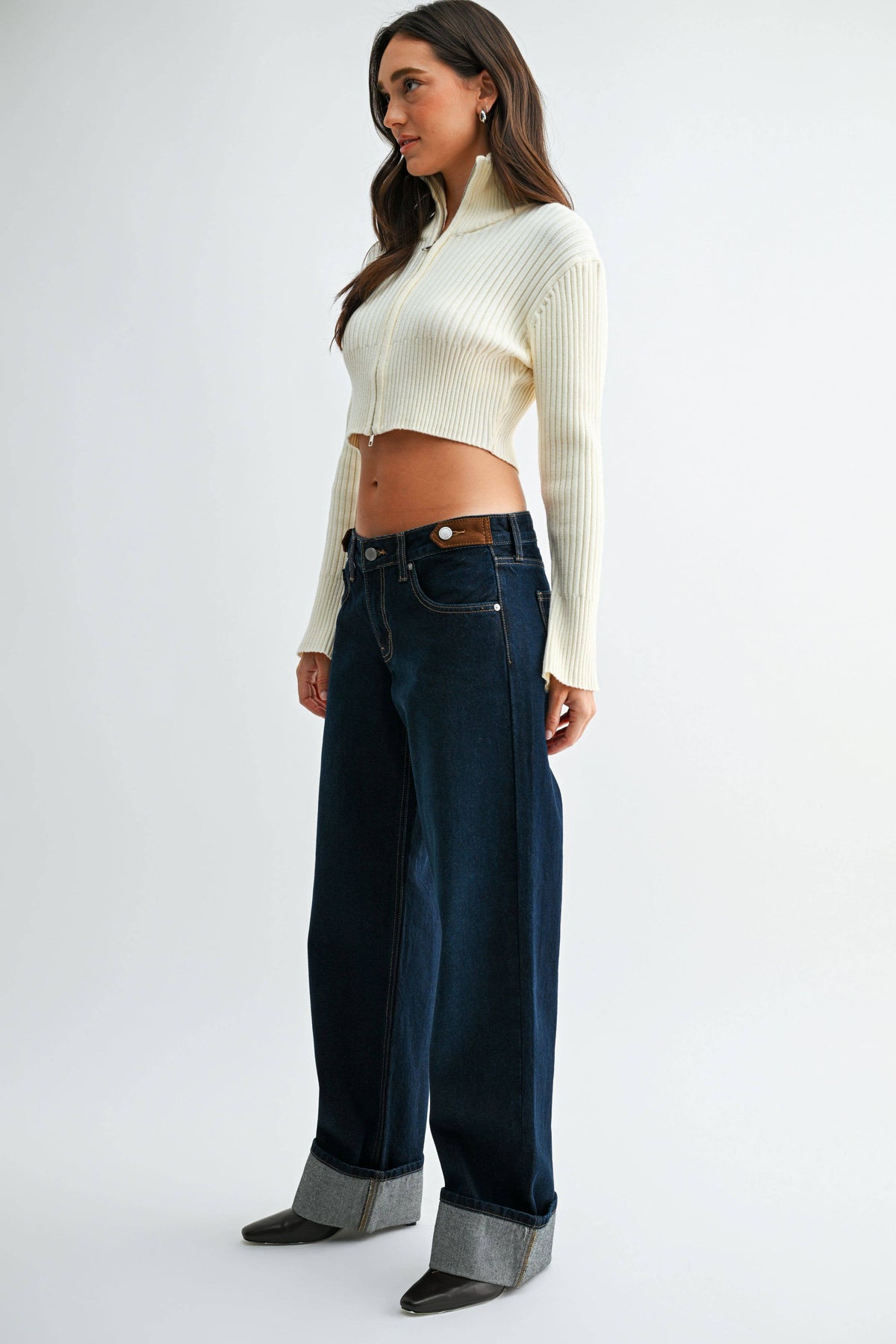 Side-angle view of Midnight Edge Cuffed Jeans showing waistband tabs, a relaxed fit, and wide rolled cuffs.
