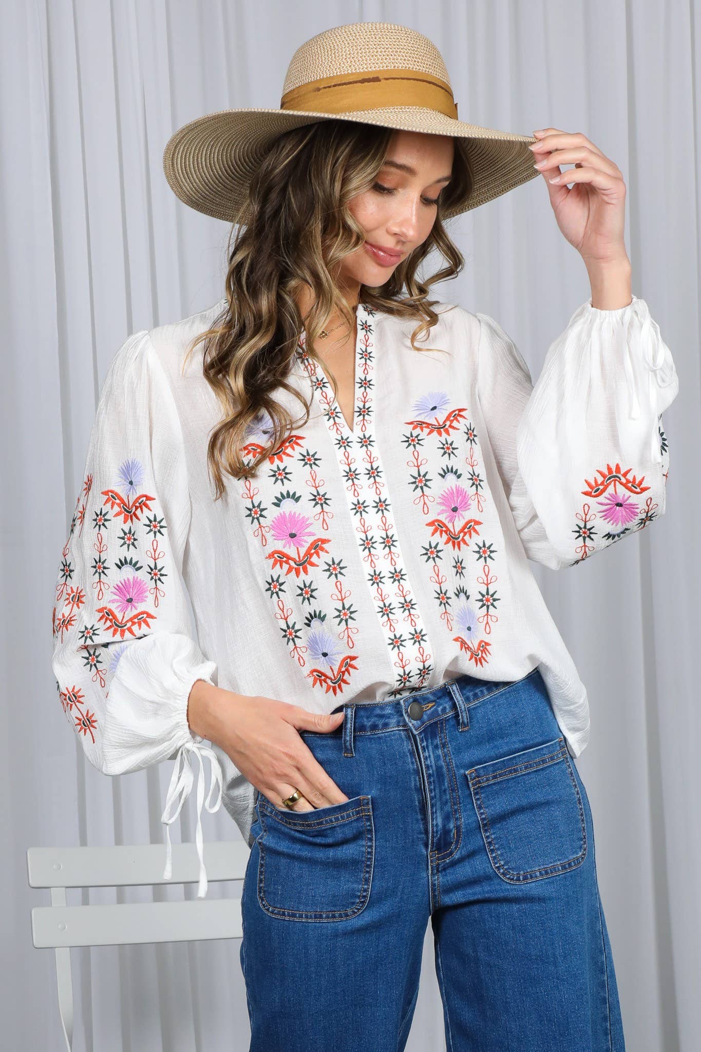 White embroidered peasant blouse with multicolor floral front, split V-neck, and balloon sleeves with ties