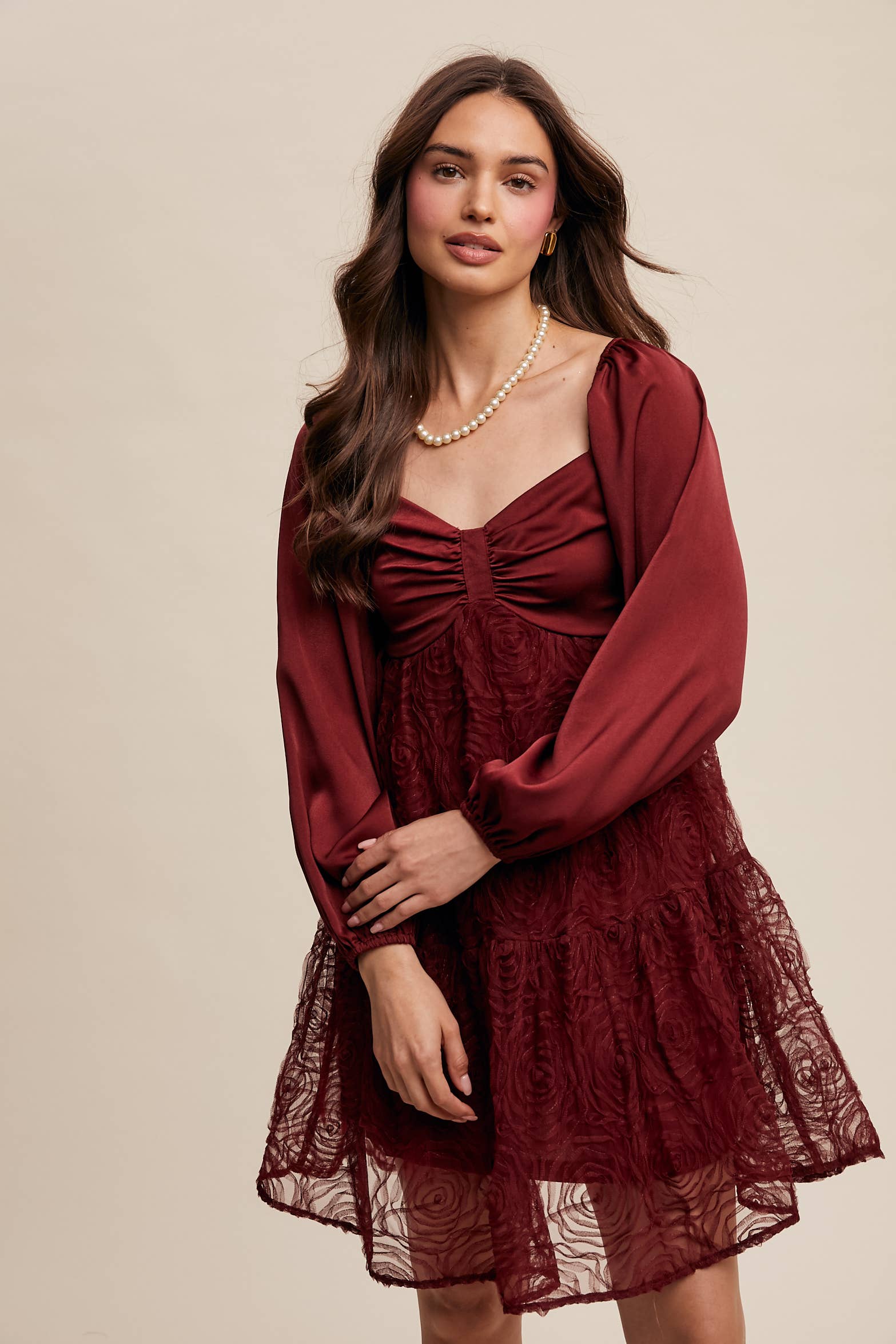 Model wearing oxblood red rosette mini dress with ruched sweetheart neckline, puff long sleeves, and tiered lace skirt — elegant and romantic look.