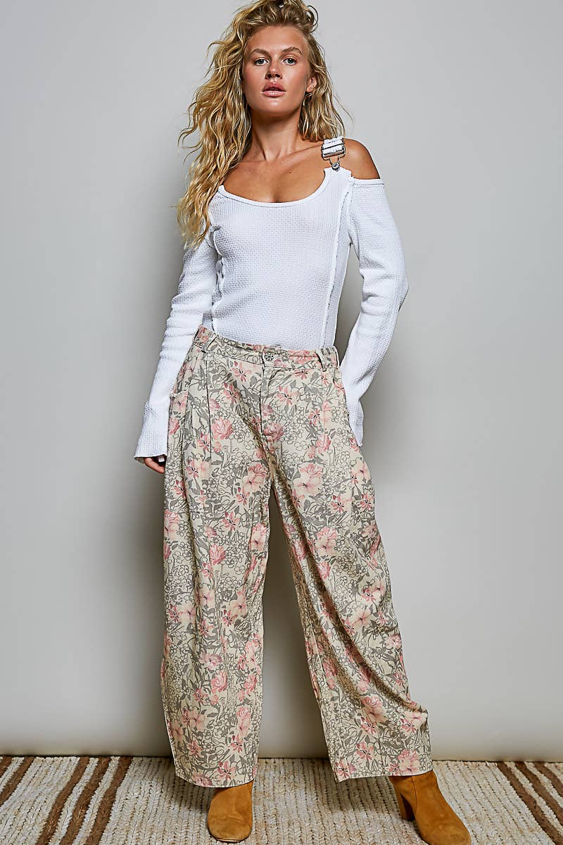 Woman wearing a white top and floral pants against a plain background