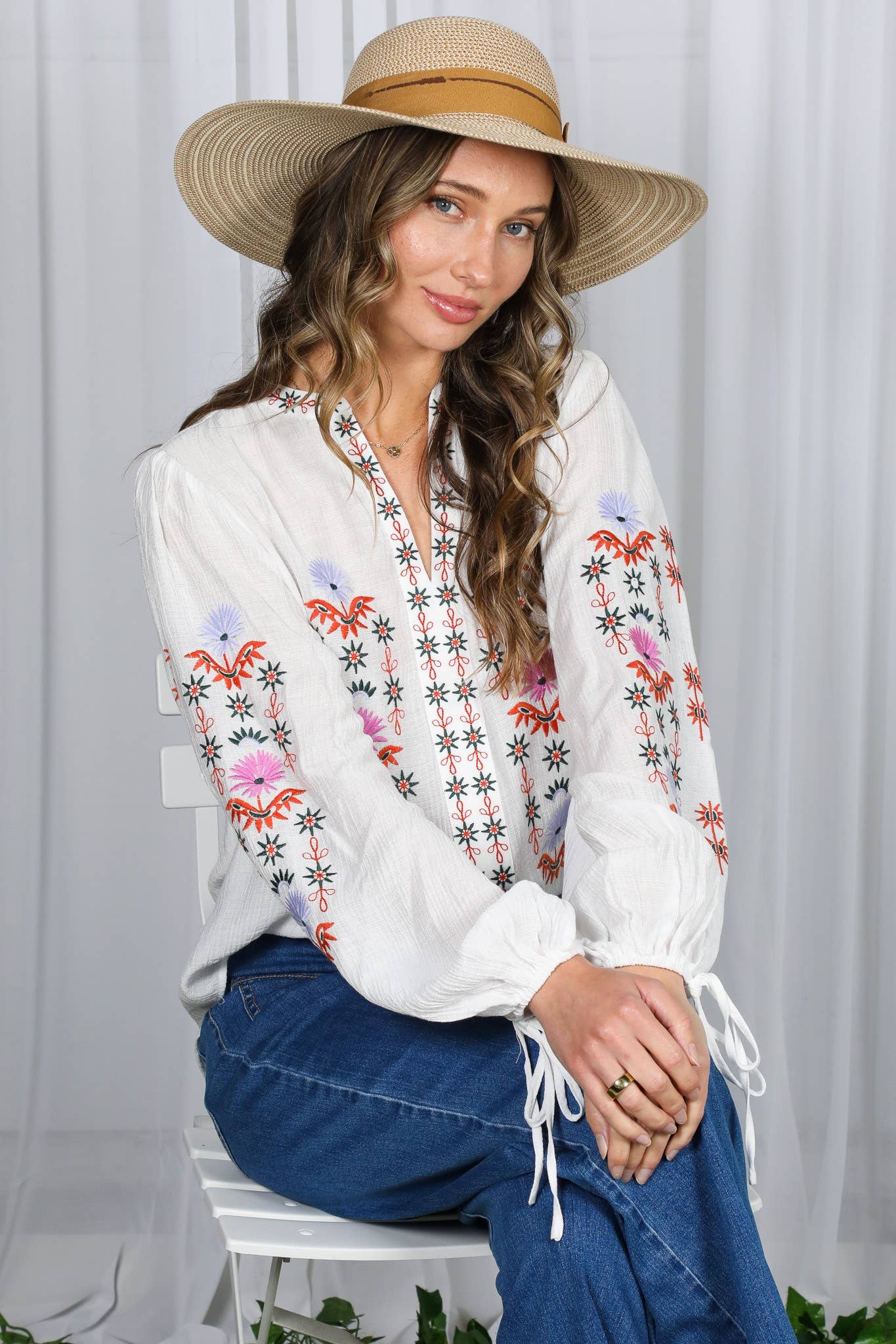 White embroidered peasant blouse with multicolor floral front, split V-neck, and balloon sleeves with ties