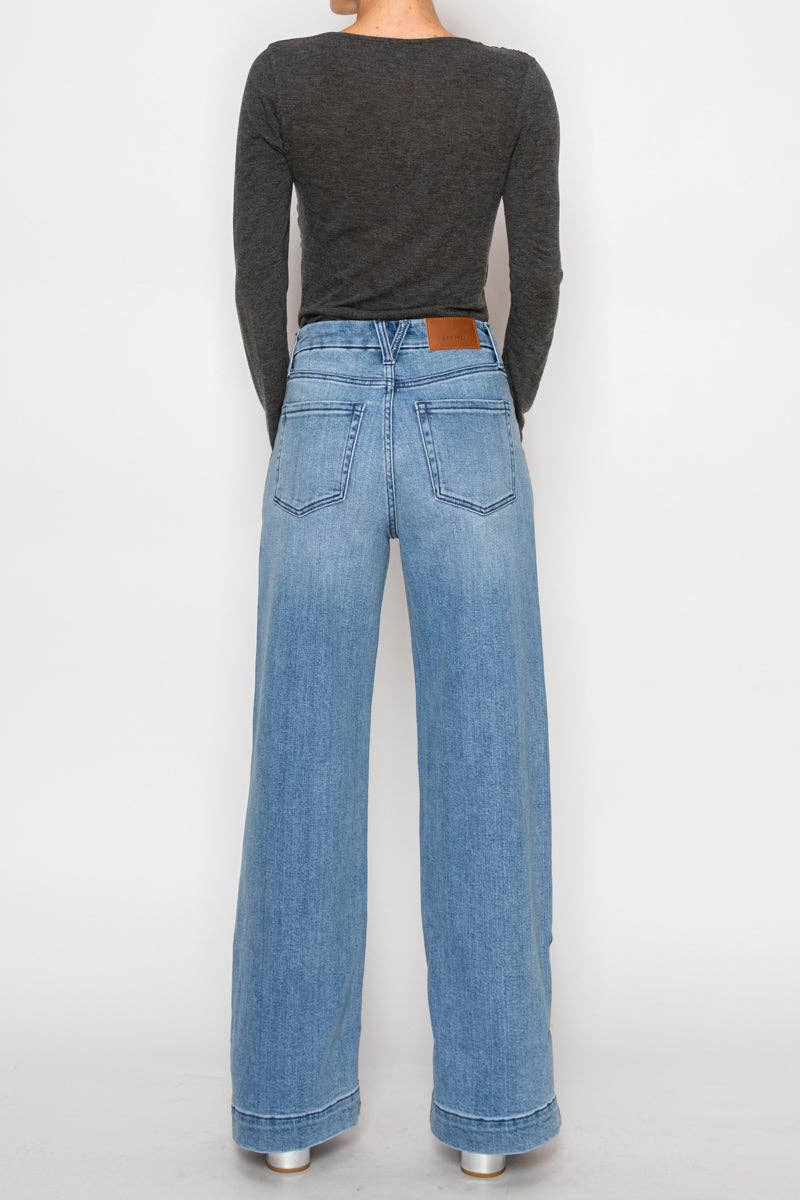Rear view of model wearing ultra high-rise wide-leg jeans in medium stone wash with cuff detail and button accents along the leg