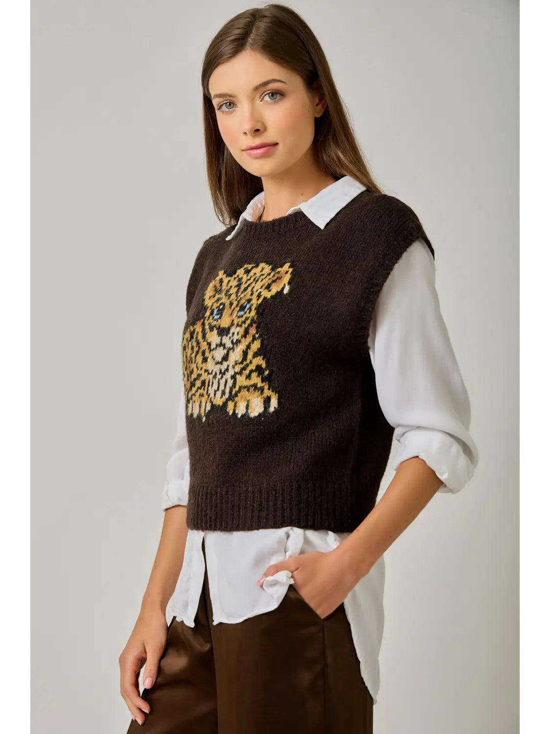 Angled front view of the Mystree brown leopard cub sweater vest layered over a white collared shirt with brown trousers.
