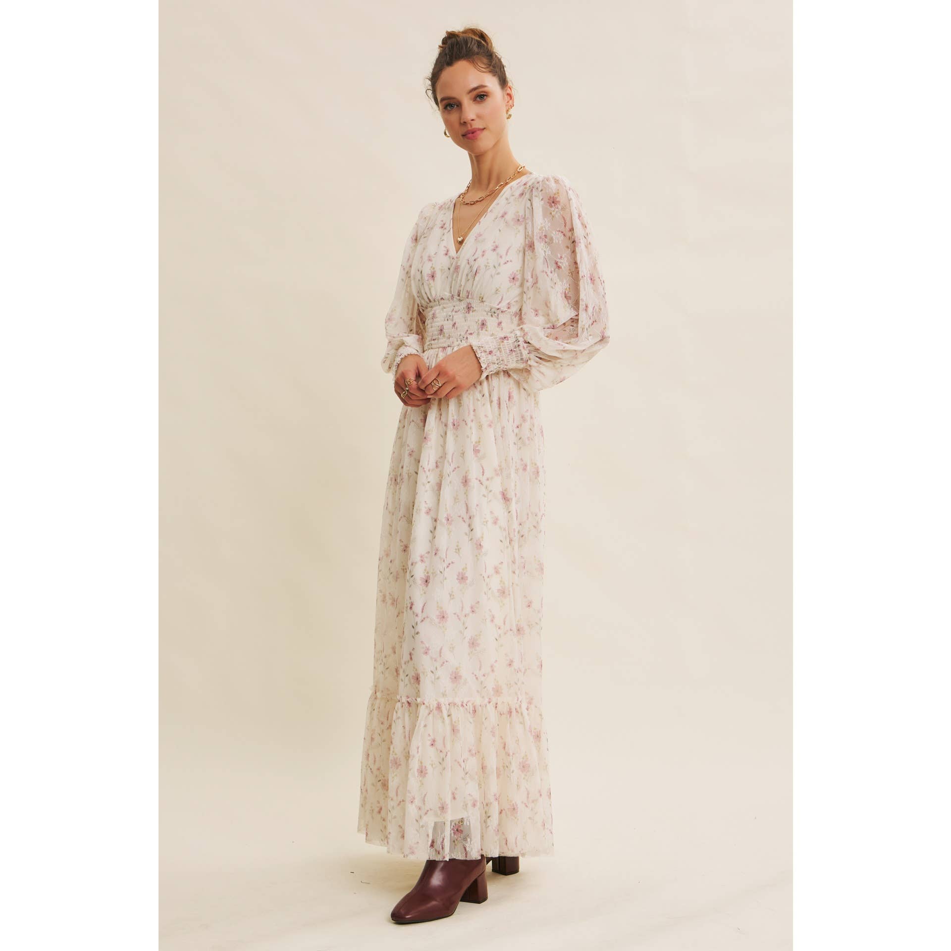 Side view — cream floral chiffon maxi dress with V-neck, sheer long sleeves, smocked waist, and ruffle hem; styled with brown boots.