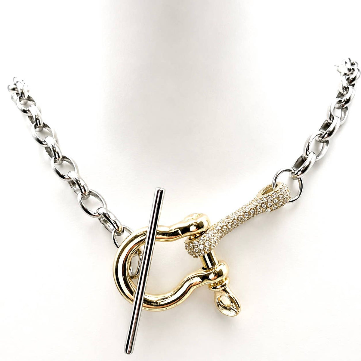 A silver chain necklace with a toggle clasp featuring a gold-toned bone-shaped accent paved with small clear stones, displayed on a white mannequin bust.