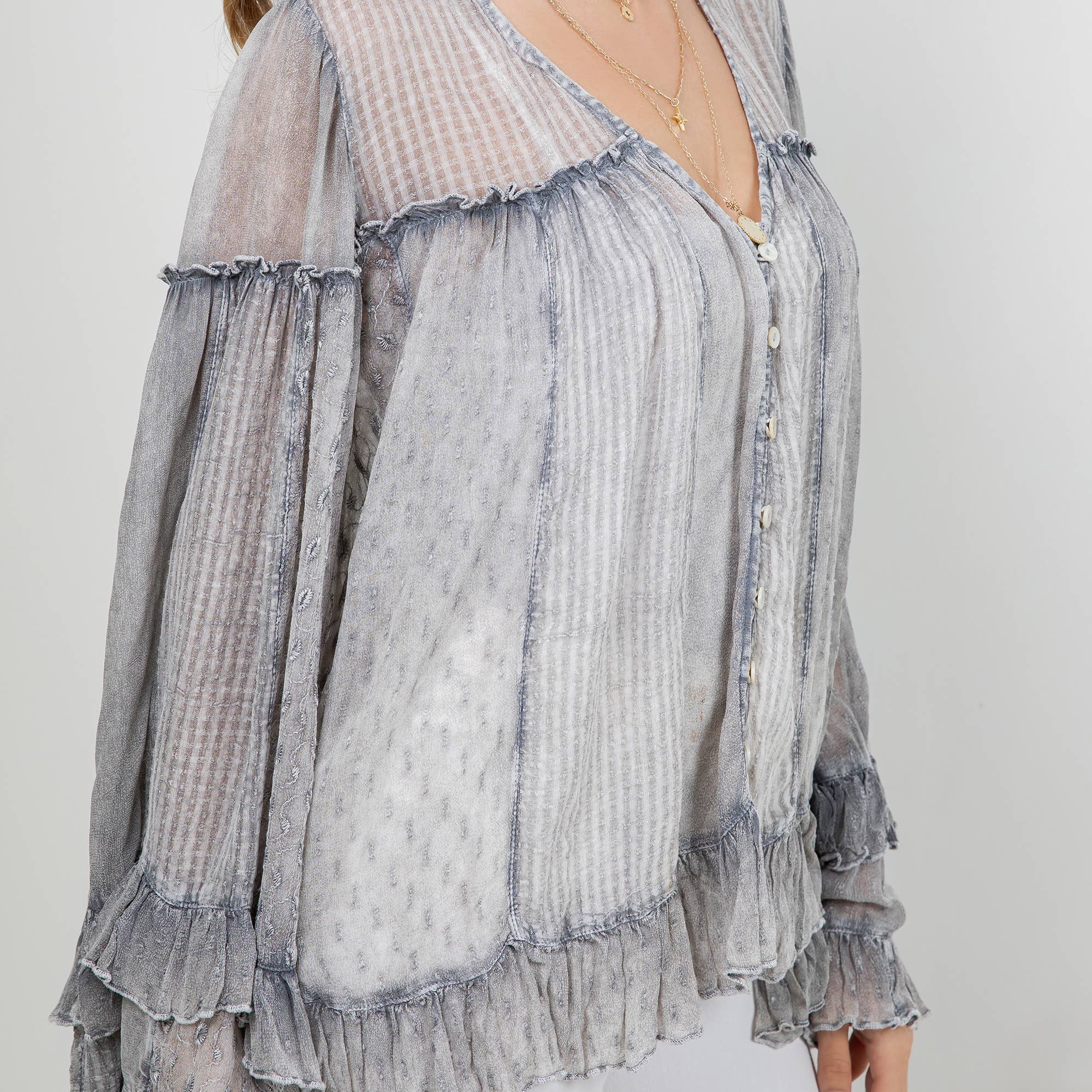 The Reverie Sheer Ruffled Blouse in Grey - detail shot of V-neckline and romantic ruffle sleeves
