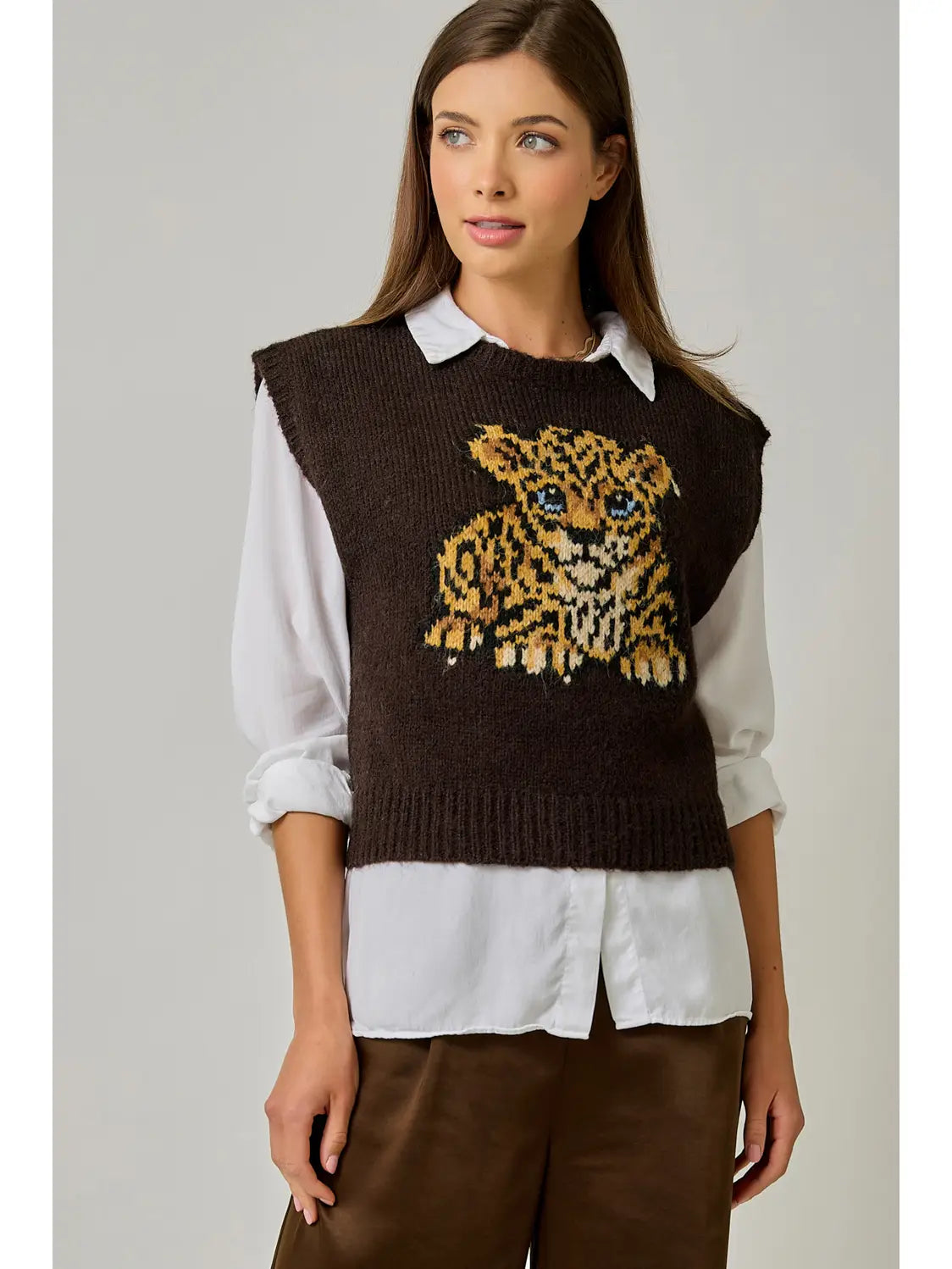 Front view of a model wearing a brown leopard cub sweater vest with extended shoulders over a white button-down shirt.
