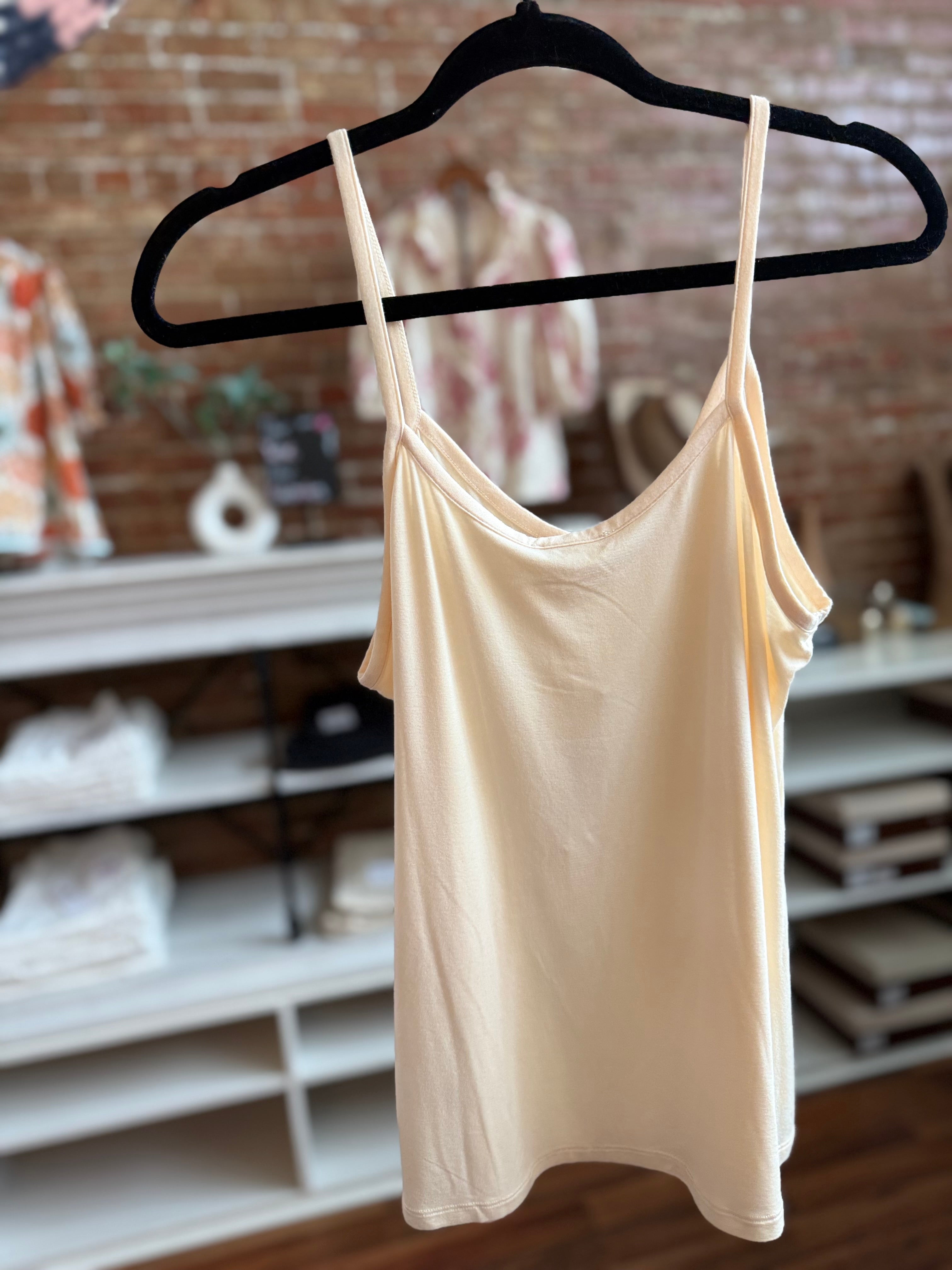 Beige tank top on a hanger against a brick wall background