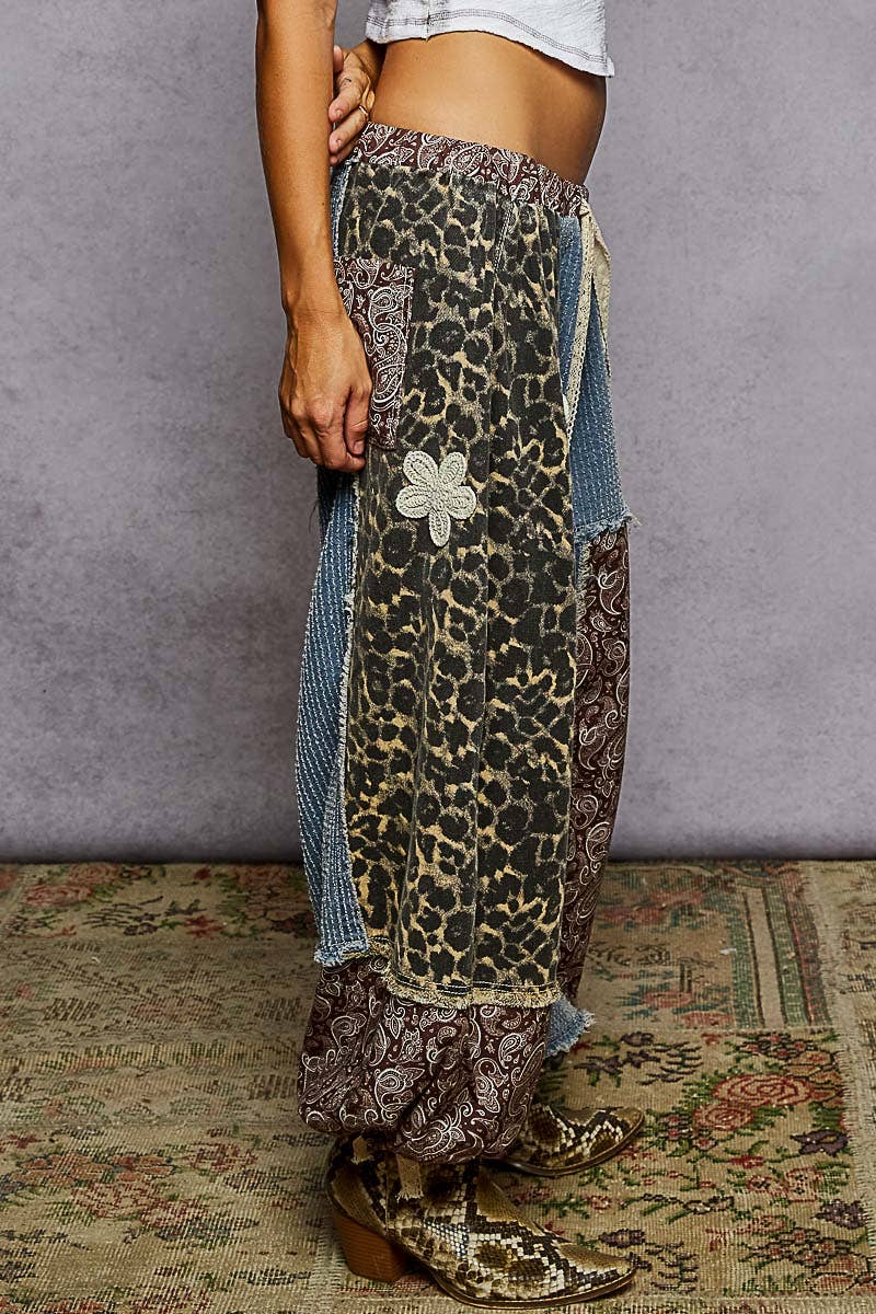 Person wearing a leopard print skirt with denim patches on a textured floor.