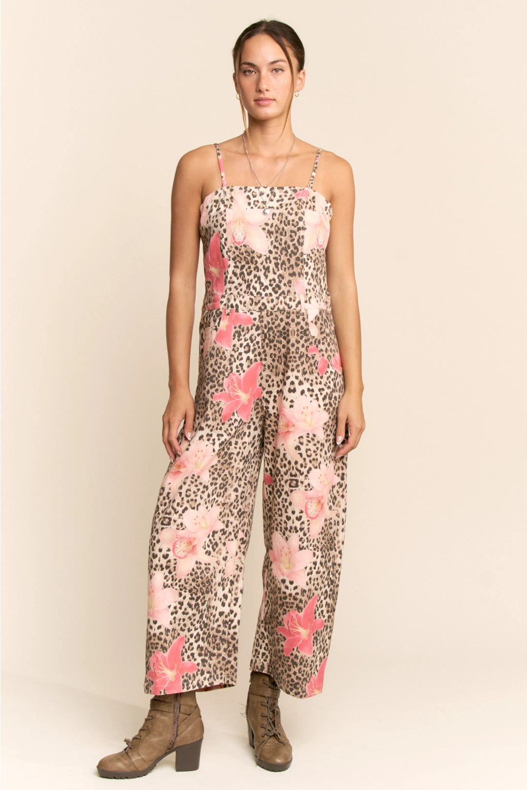 Woman wearing a floral and animal print jumpsuit on a plain background