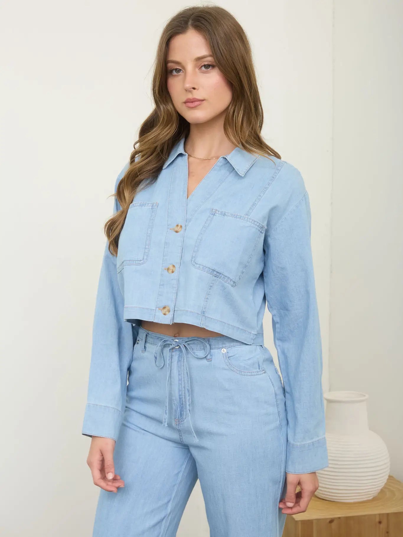 Woman wearing a light blue denim outfit against a white background