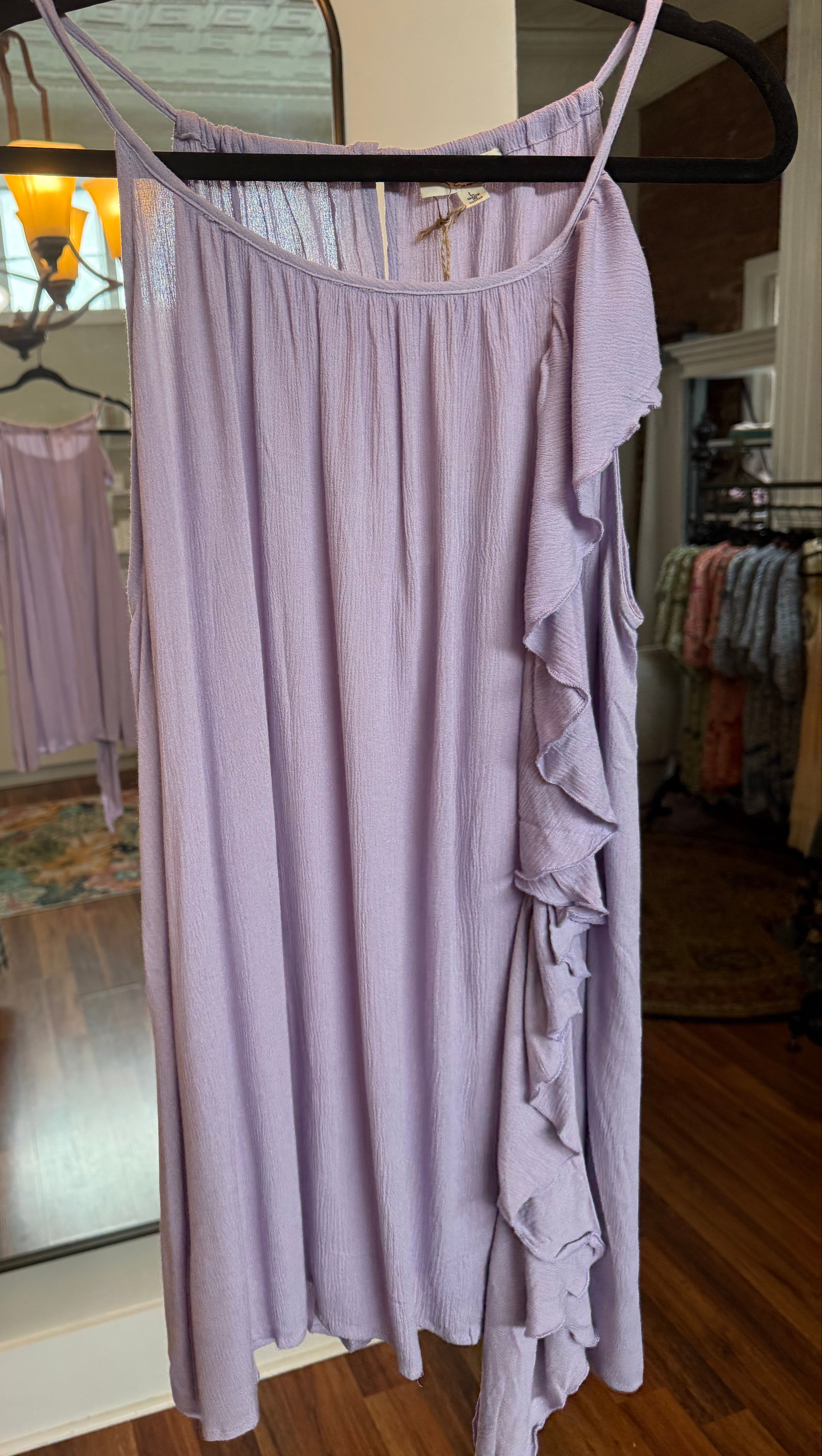 Light purple dress on a mannequin in a room with a mirror reflecting a person and furniture.
